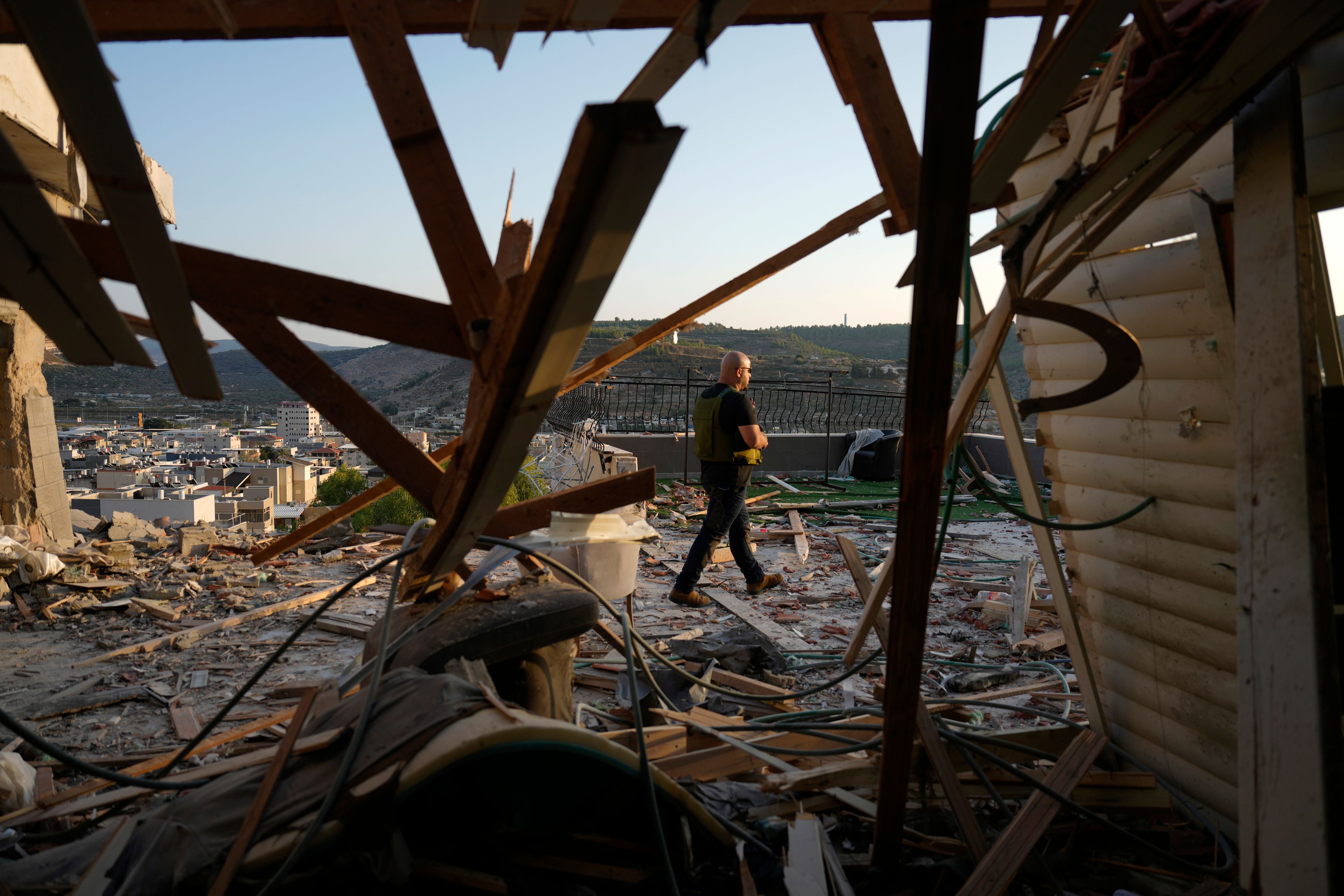 Israeli security forces survey damage to a home struck by a rocket fired from Lebanon in the town of Majd al-Krum, northern Israel, Wednesday, Oct. 16, 2024. (AP Photo/Ariel Schalit)