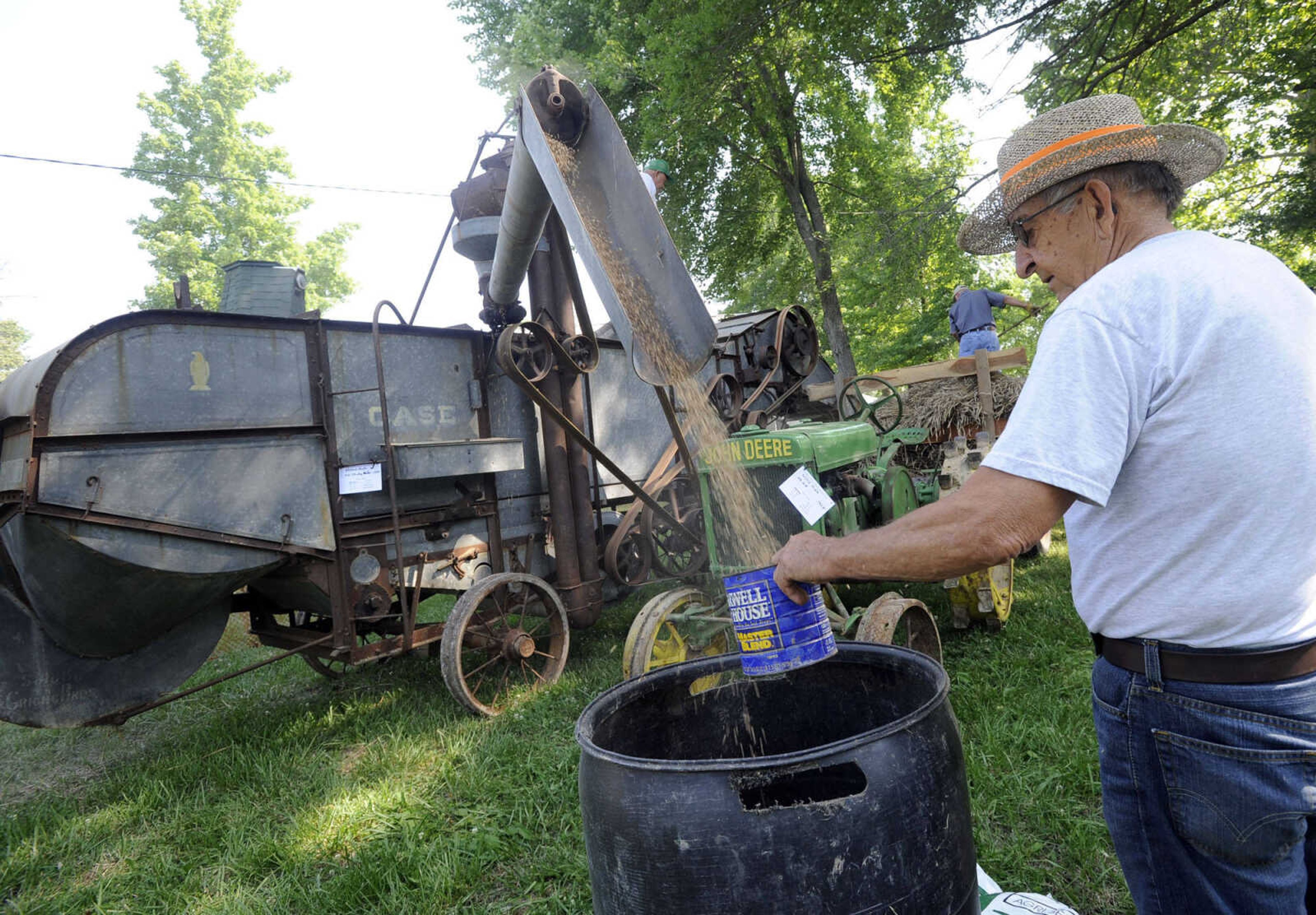 Dale Prevallet collects the finished product from Willard Hadler's 1935 Case thresher Saturday at Old Timers' Day in Perryville, Mo.