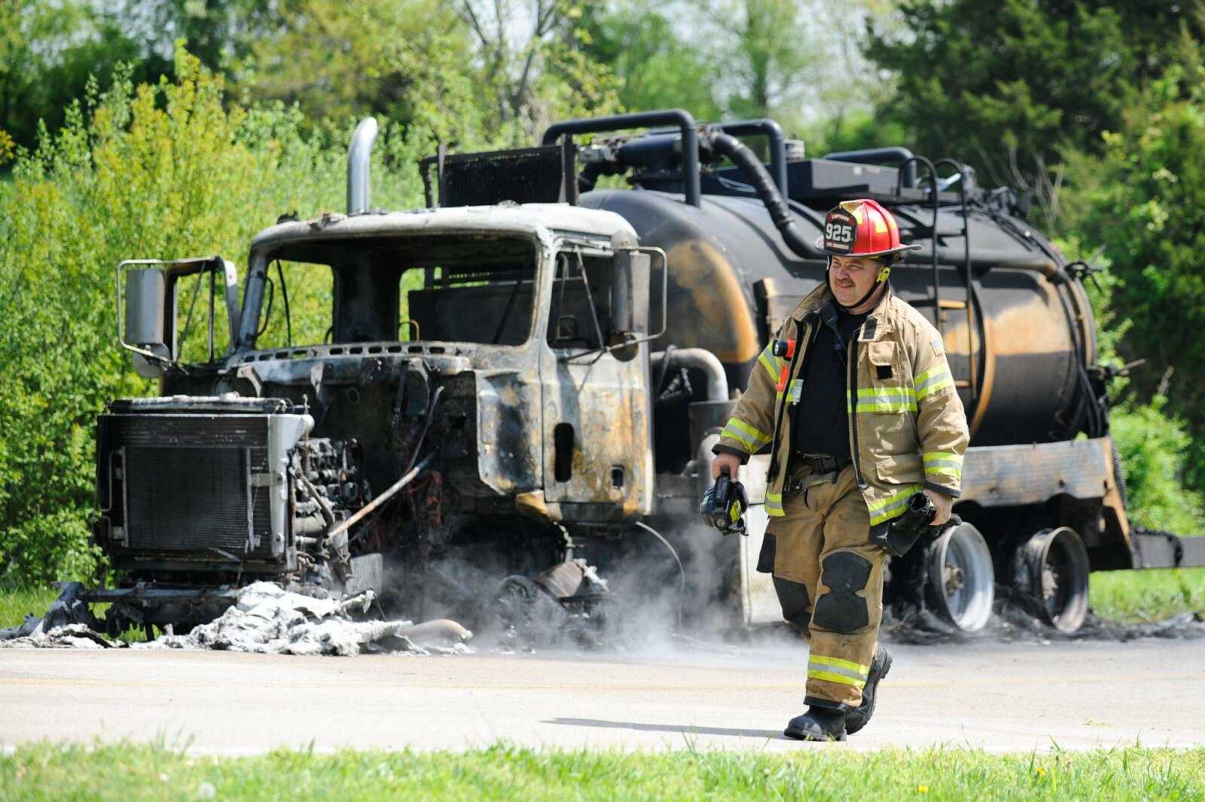 A member of the Cape Girardeau Fire Department walks past the charred remains of a truck involved in an accident on Highway E near Oak Ridge, Missouri Friday, April 22, 2016. An automobile traveling east, crossed the center line and collided with a tanker truck headed south, just after 11:00 a.m. Both drivers were transported to Saint Francis Medical Center.