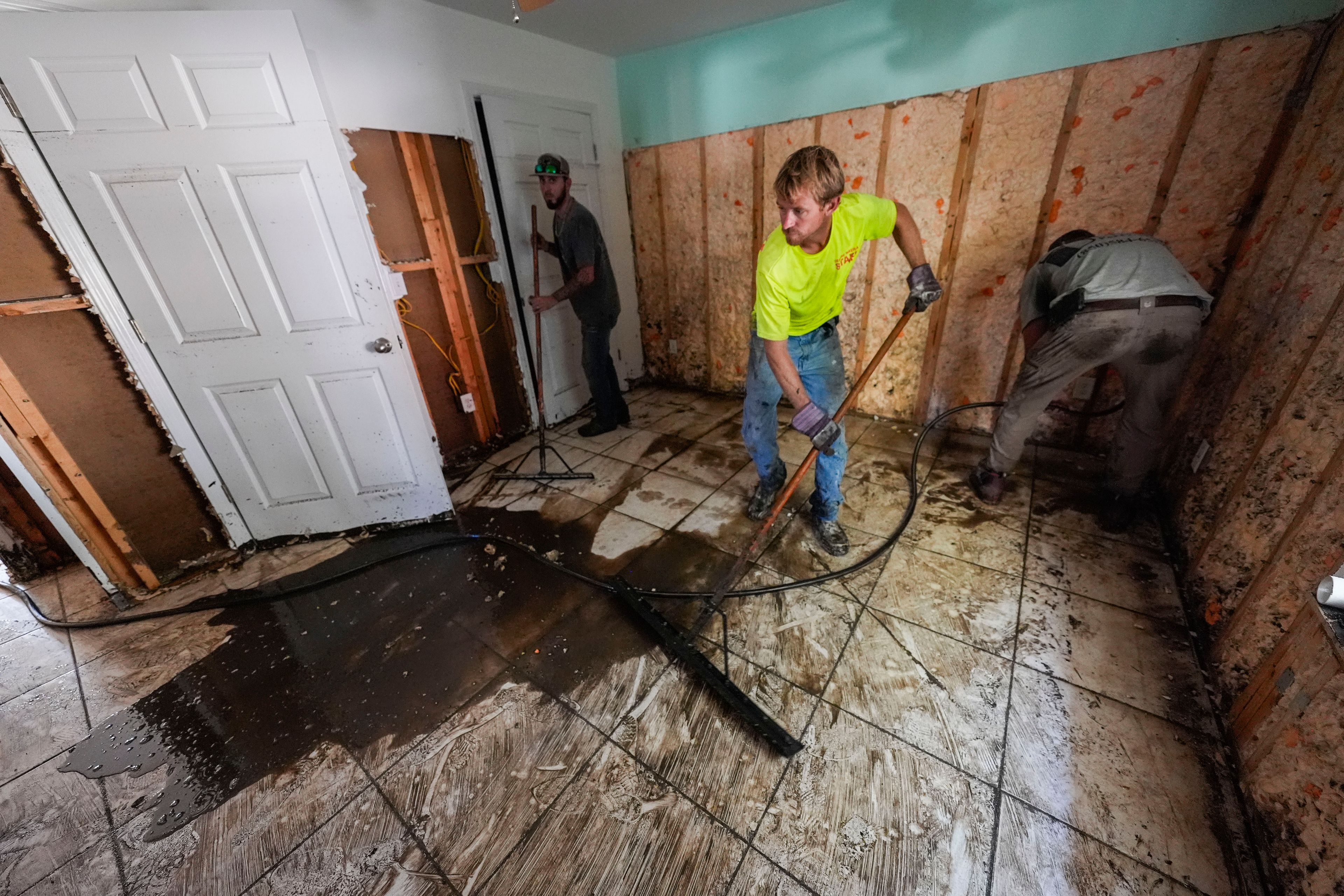 Workers clean and gut a property that was flooded from the storm surge, in the aftermath of Hurricane Helene, in Steinhatchee, Fla., Sunday, Sept. 29, 2024. (AP Photo/Gerald Herbert)