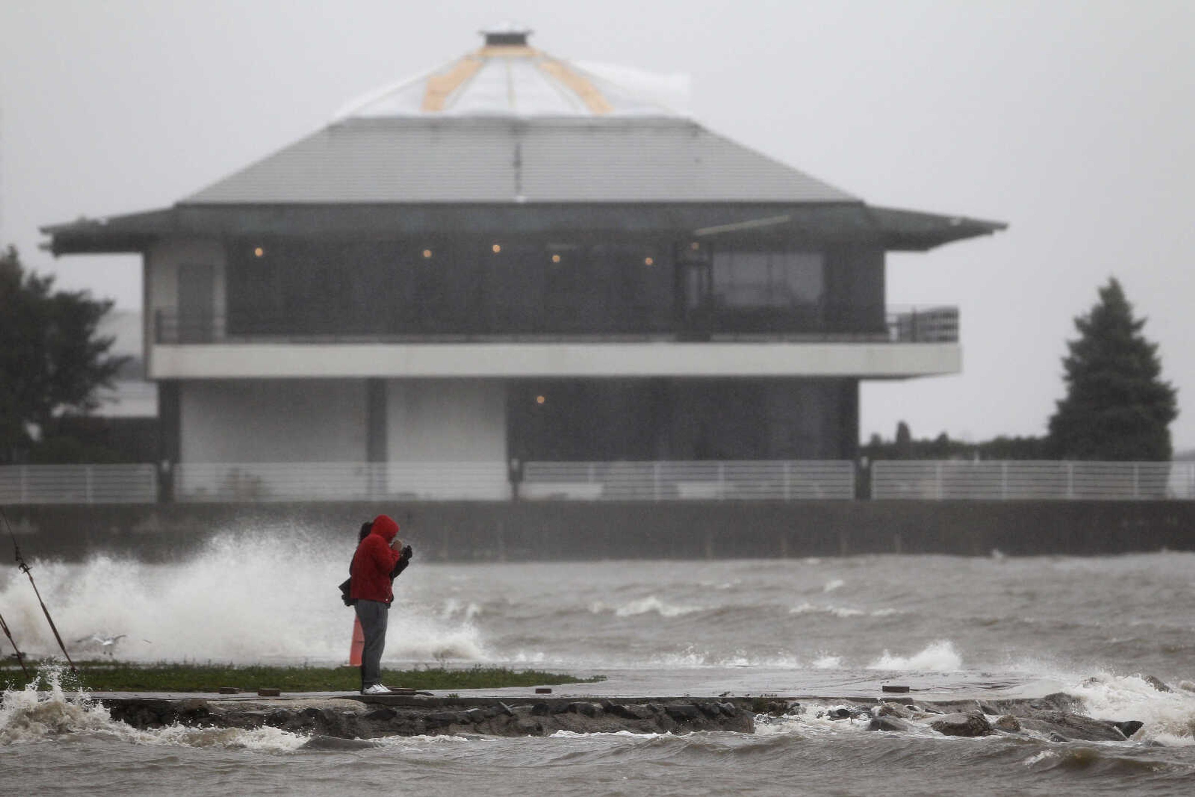 Javier Gutierrez, front, stands with his daughter Ashley Gutierrez as they check out what Hurricane Sandy is doing to the Hudson River, Monday, Oct. 29, 2012, in Weehawken, N.J. Hurricane Sandy continued on its path Monday, as the storm forced the shutdown of mass transit, schools and financial markets, sending coastal residents fleeing, and threatening a dangerous mix of high winds and soaking rain. (AP Photo/Julio Cortez)