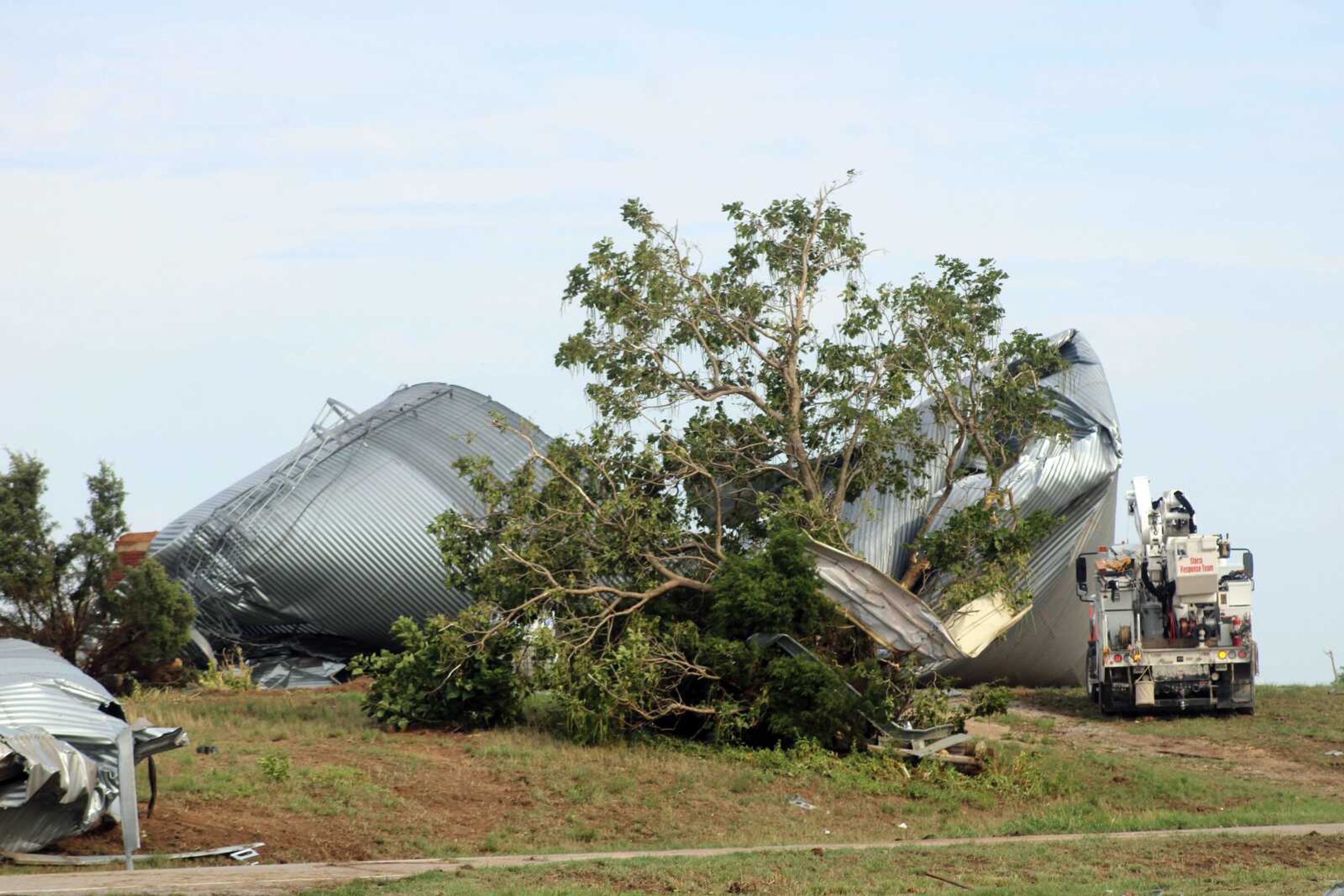 Work crews make their way to a grain silo near the intersection of Route O and County Road 532 that was destroyed during a storm Monday, July 24, in Scott County.