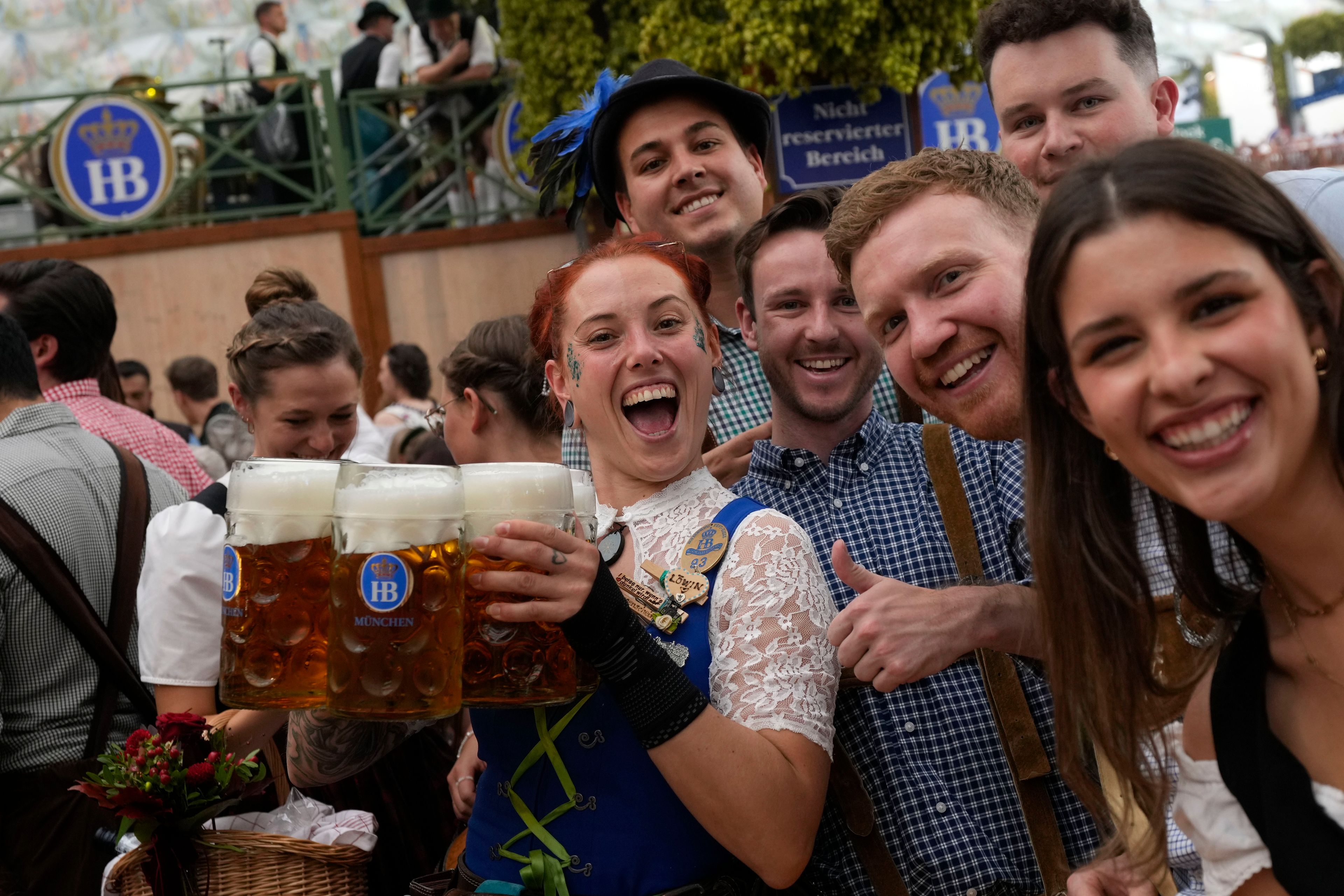 A waitress poses with guests at the Hofbraeuhaus beer tent on day one of the 189th 'Oktoberfest' beer festival in Munich, Germany, Saturday, Sept. 21, 2024. (AP Photo/Matthias Schrader)