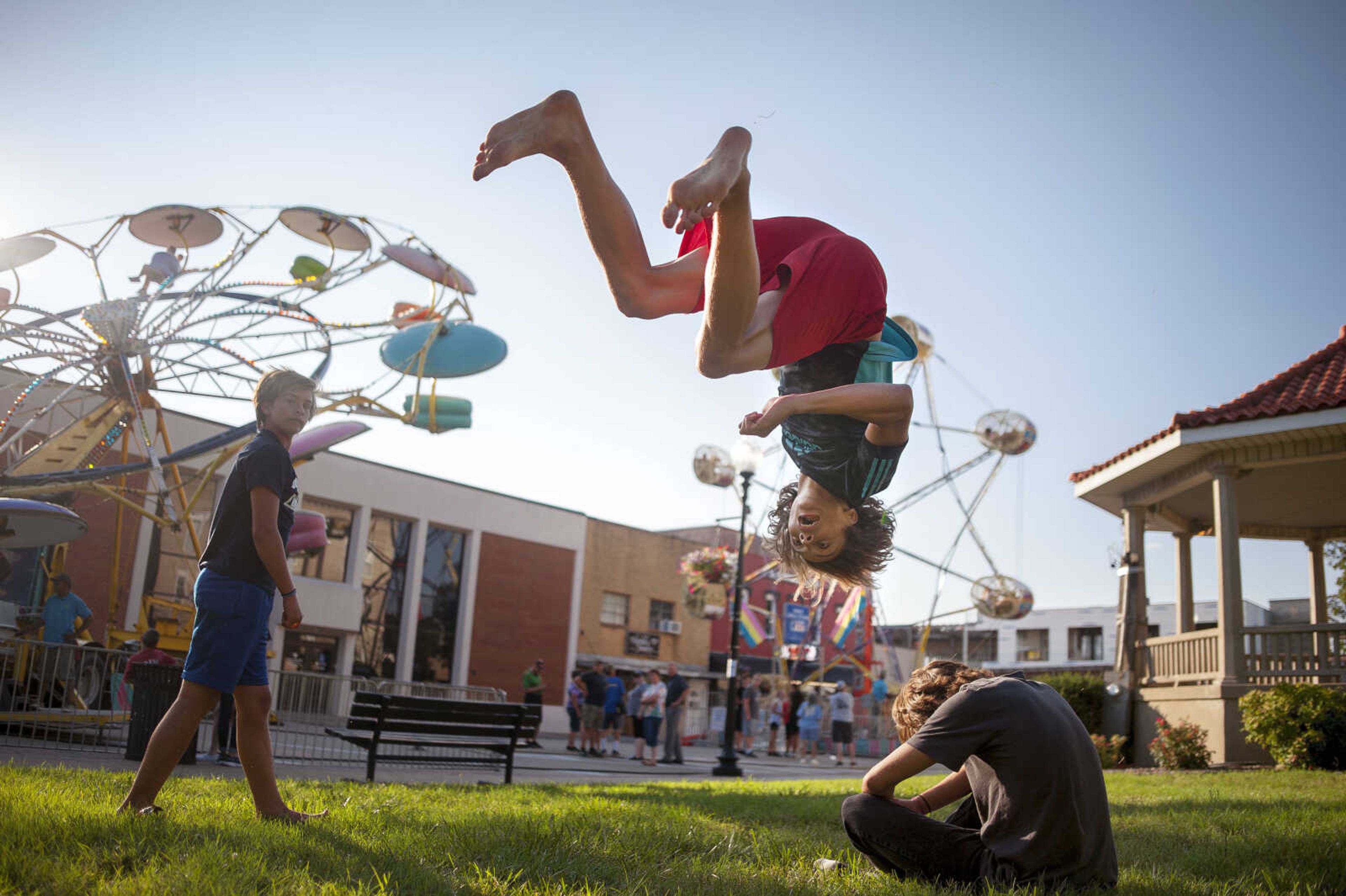 Dawson Jackson,15, center, backflips over his friend, Matthew Sturm, 16, as another friend, Christopher Mellon, 13, waches on the courthouse lawn during Homecomers Tuesday, July 23, 2019, in Uptown Jackson. The boys said they taught themselves how to do backflips, back handsprings and other acrobatics in their backyards over the past 5 years as a hobby. "It just looked cool," Jackson said.