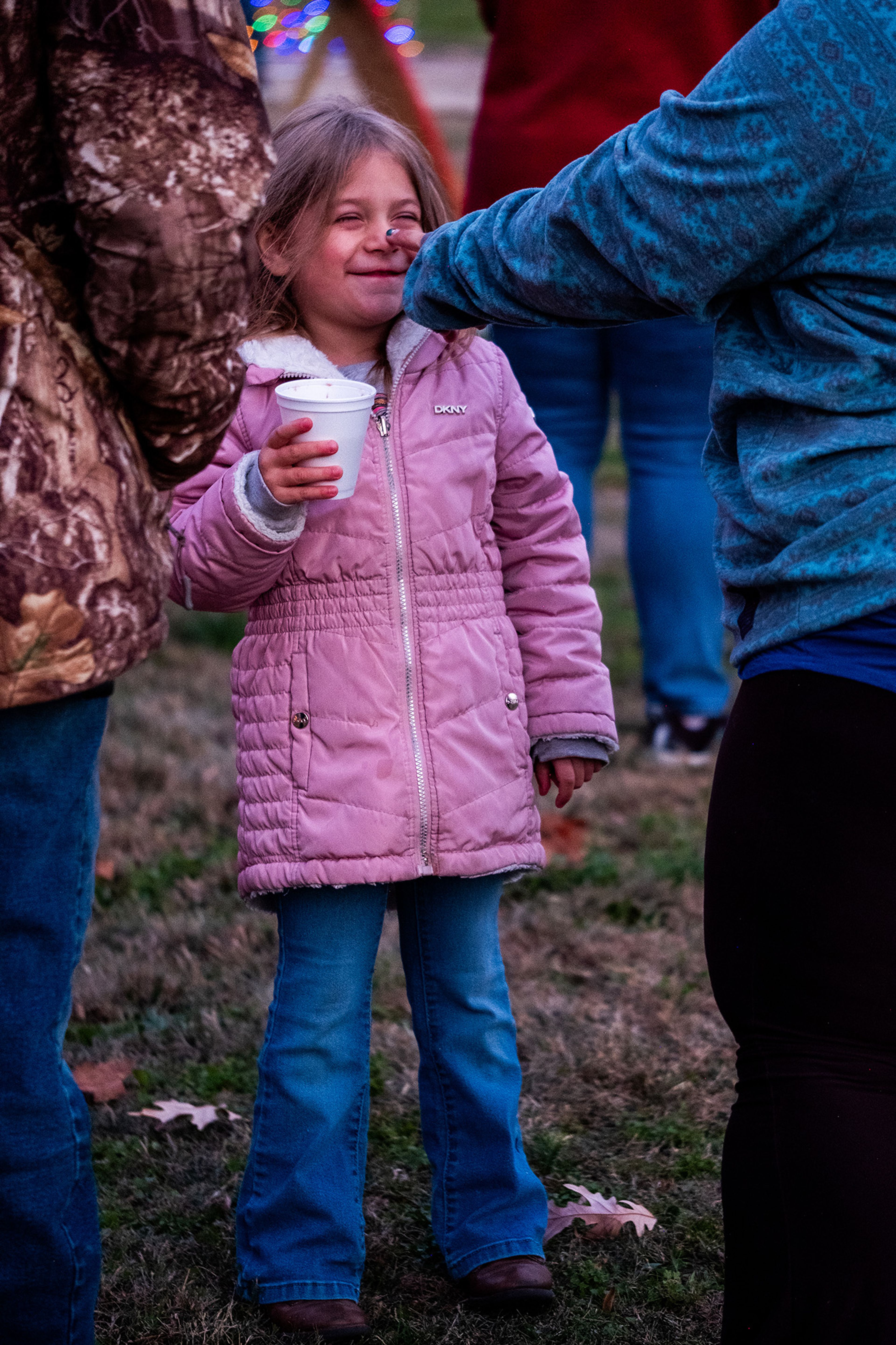 A mother playfully taps her daughter's nose, careful not to spill her hot chocolate.
