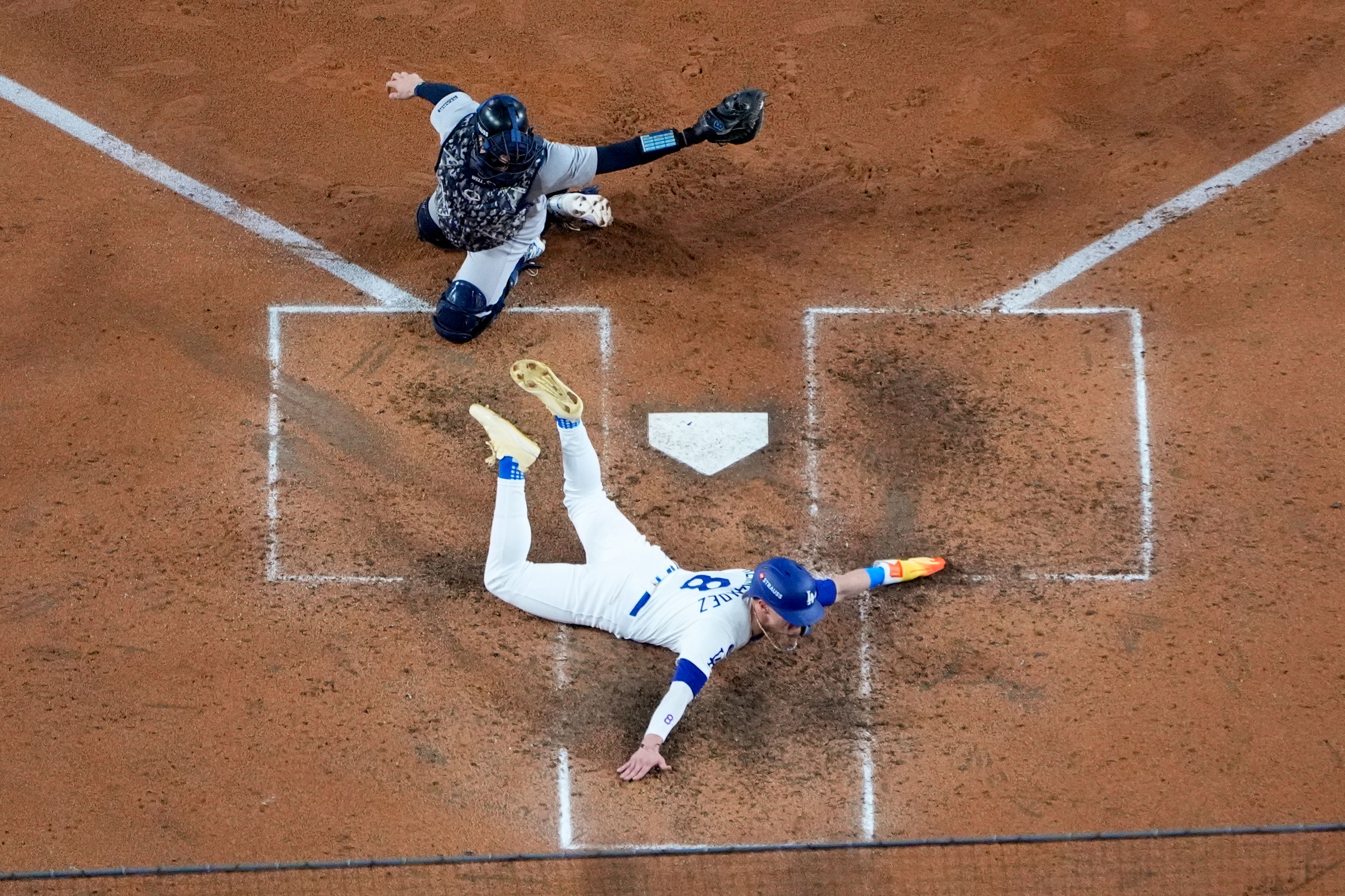 Los Angeles Dodgers' Kiké Hernández, bottom, scores past New York Yankees catcher Austin Wells on a sacrifice fly ball by Will Smith during the fifth inning in Game 1 of the baseball World Series, Friday, Oct. 25, 2024, in Los Angeles. (AP Photo/Mark J. Terrill)