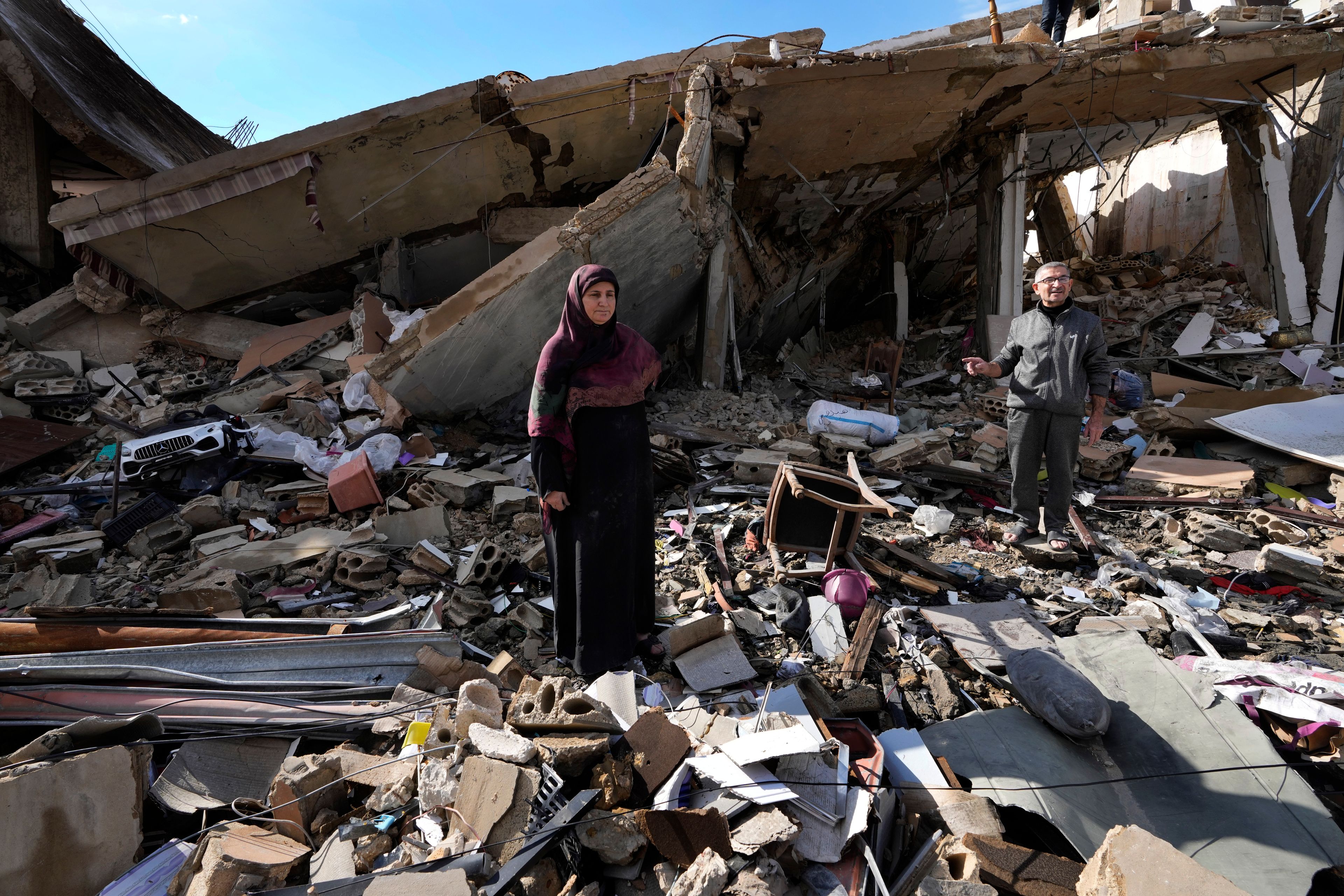 Mariam Kourani, 56, and her husband Ali Haidous, stand on the rubble of their destroyed house after they returned to their village of Hanouiyeh , southern Lebanon, Thursday, Nov. 28, 2024 following a ceasefire between Israel and Hezbollah that went into effect on Wednesday.(AP Photo/Hussein Malla)