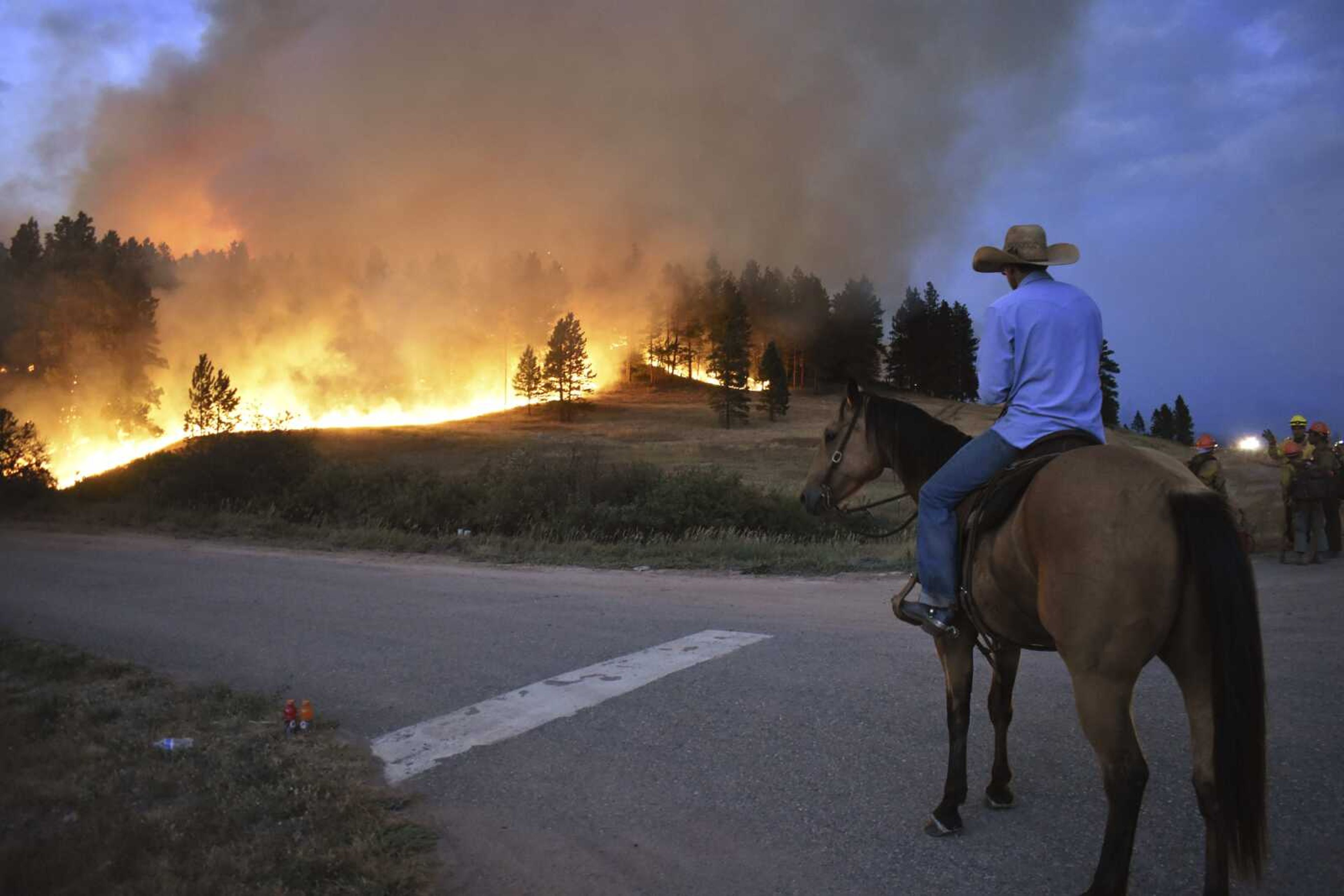 Rowdy Alexander watches from atop his horse as a hillside burns on the Northern Cheyenne Indian Reservation on Wednesday near Lame Deer, Montana.