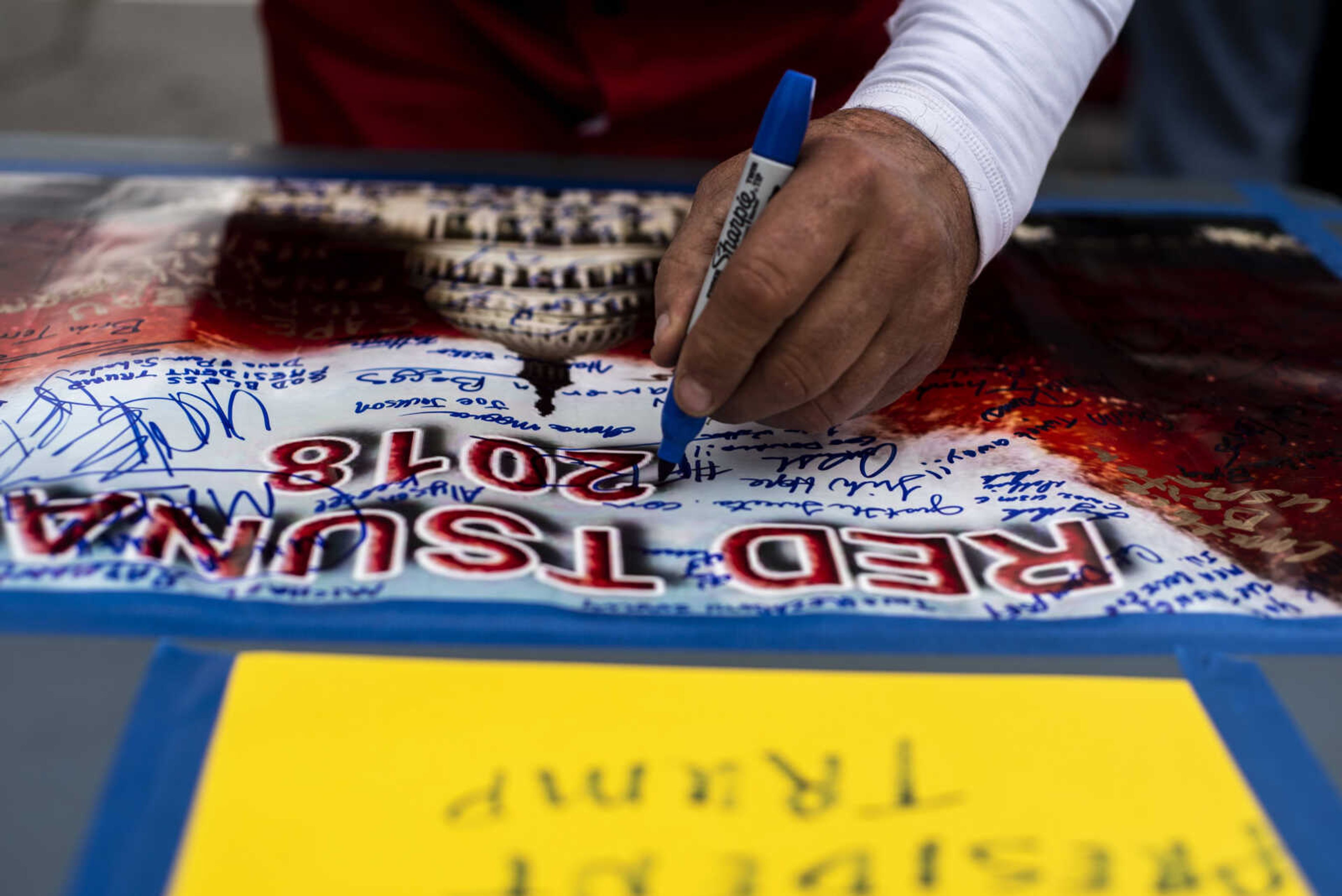 Randal Thom, 58, of Lakefield, Minnesota, signs a photo that says "Red Tsunami 2018" for President Donald Trump Monday, Nov. 5, 2018, in Cape Girardeau.