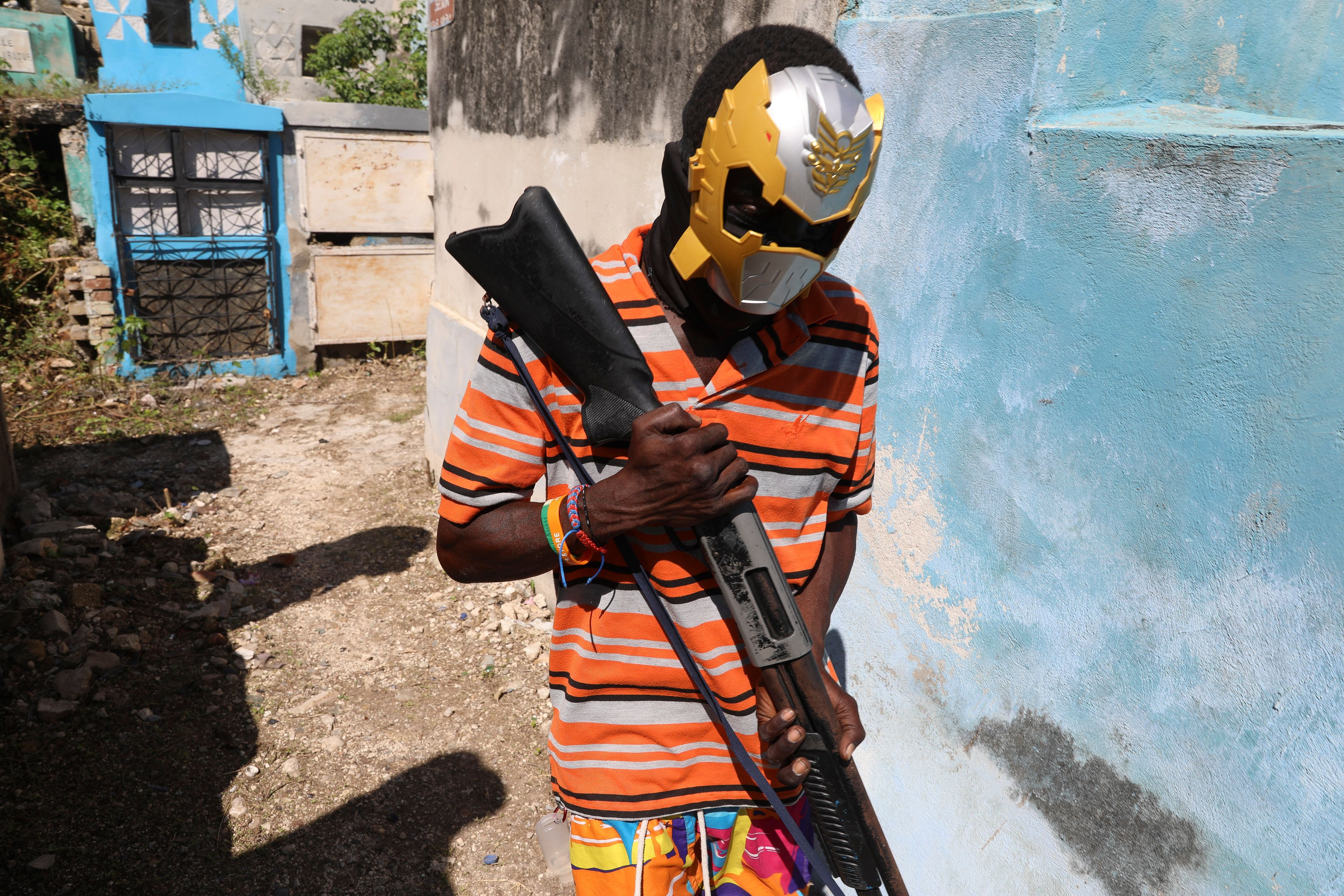 A masked gang member poses for a picture among graves during the annual Fete Gede festival that celebrates Day of the Dead, honoring the Haitian Vodou spirits Baron Samedi and Gede, at the National Cemetery, in Port-au-Prince, Haiti, Friday, Nov. 1, 2024. (AP Photo/Odelyn Joseph)