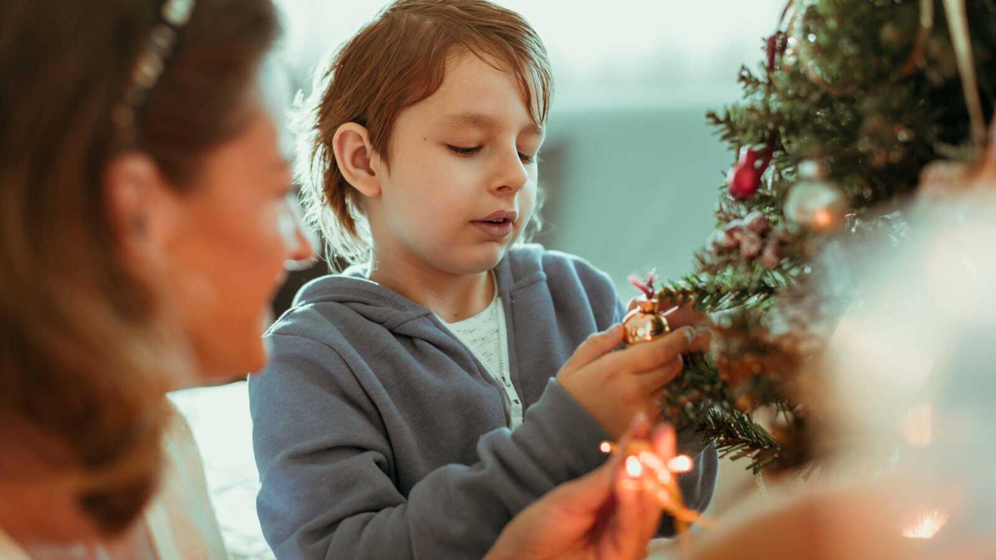 Fashion description:Mother and son decorate a small Christmas tree.