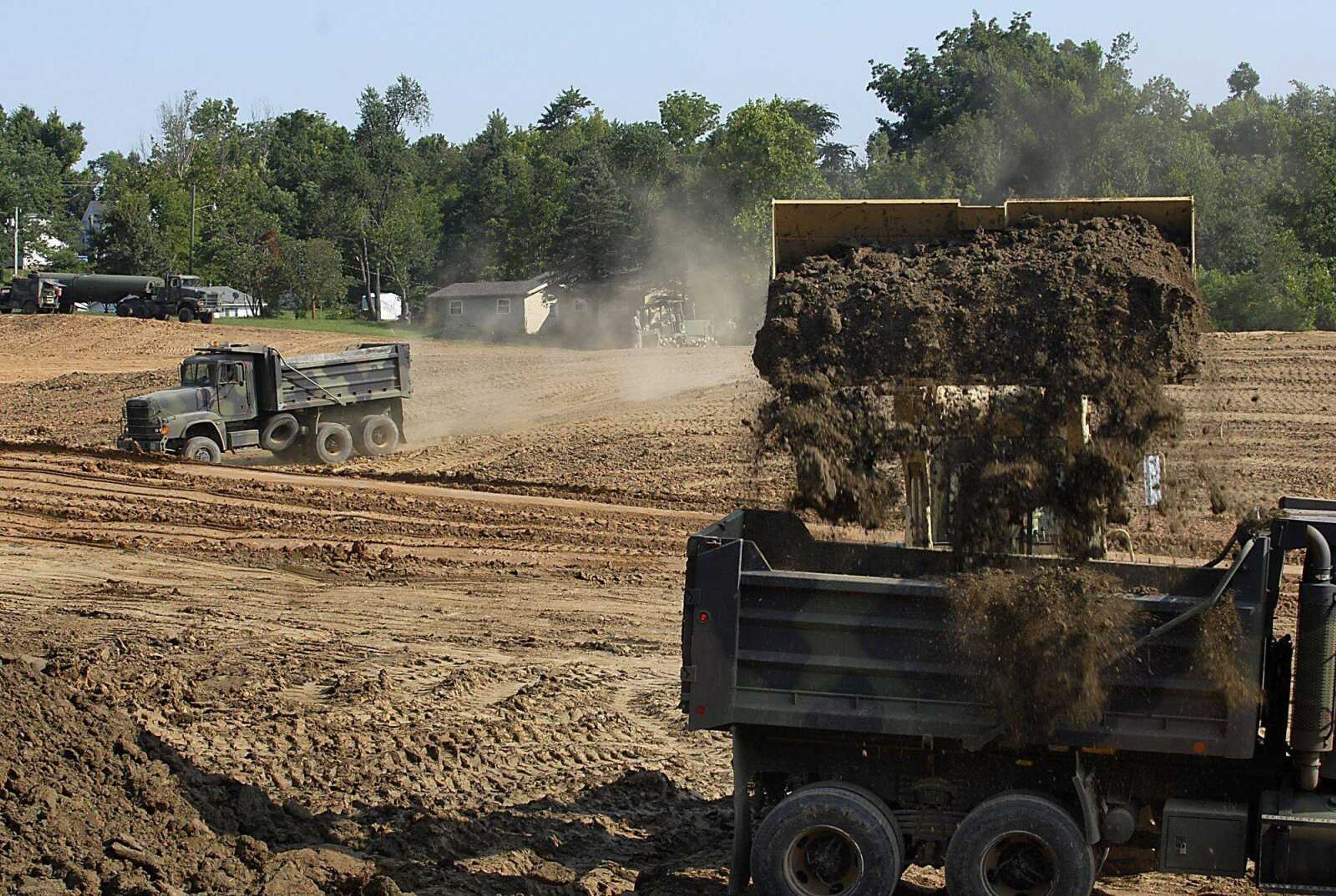 National Guard dump trucks on Friday take top soil from the north side of Brookside Park to top off an area on the south side of the Jackson park. (Kit Doyle)