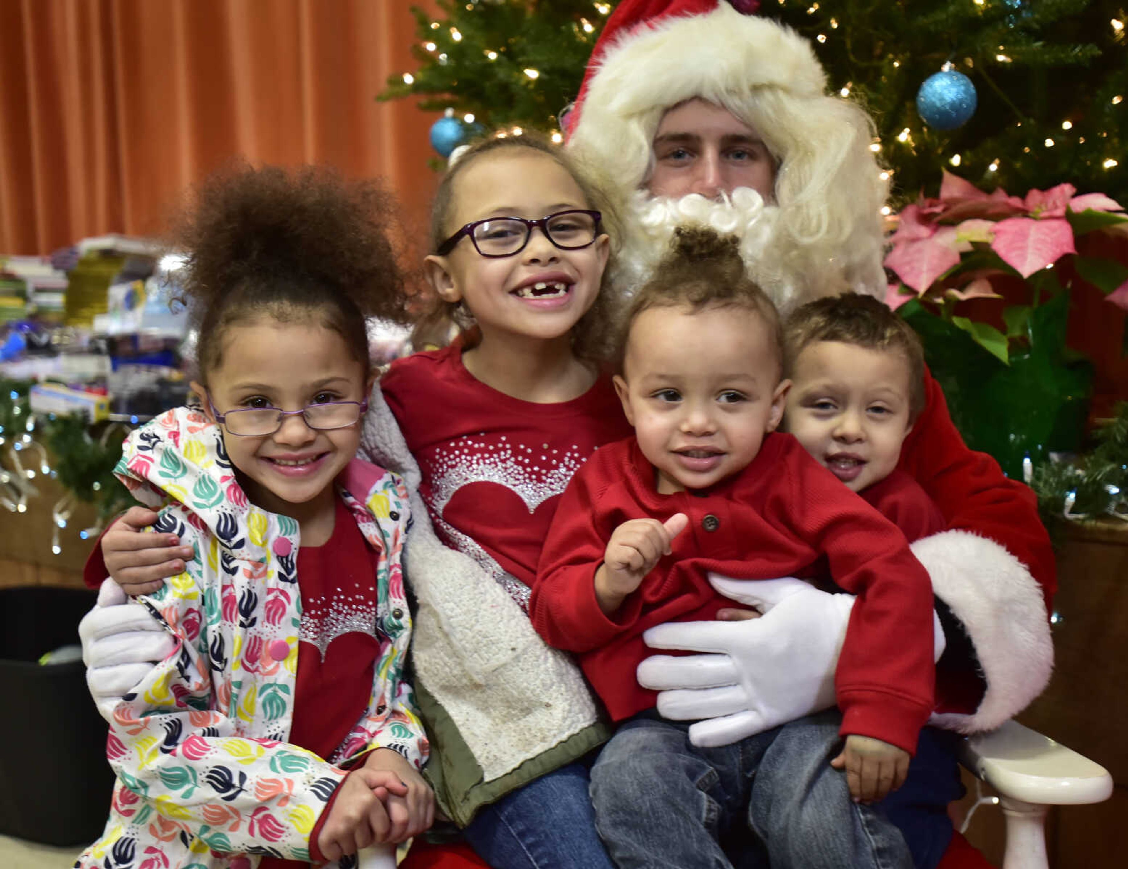 From left, Aubri Barnhill, 5, Areiya Barnhill, 7, Kache Barnhill, 1, and Delrease Barnhill, 3, sits on Santa's lap during a free lunch hosted by Student Santas on Dec. 25, 2017, at Jefferson Elementary School in Cape Girardeau.