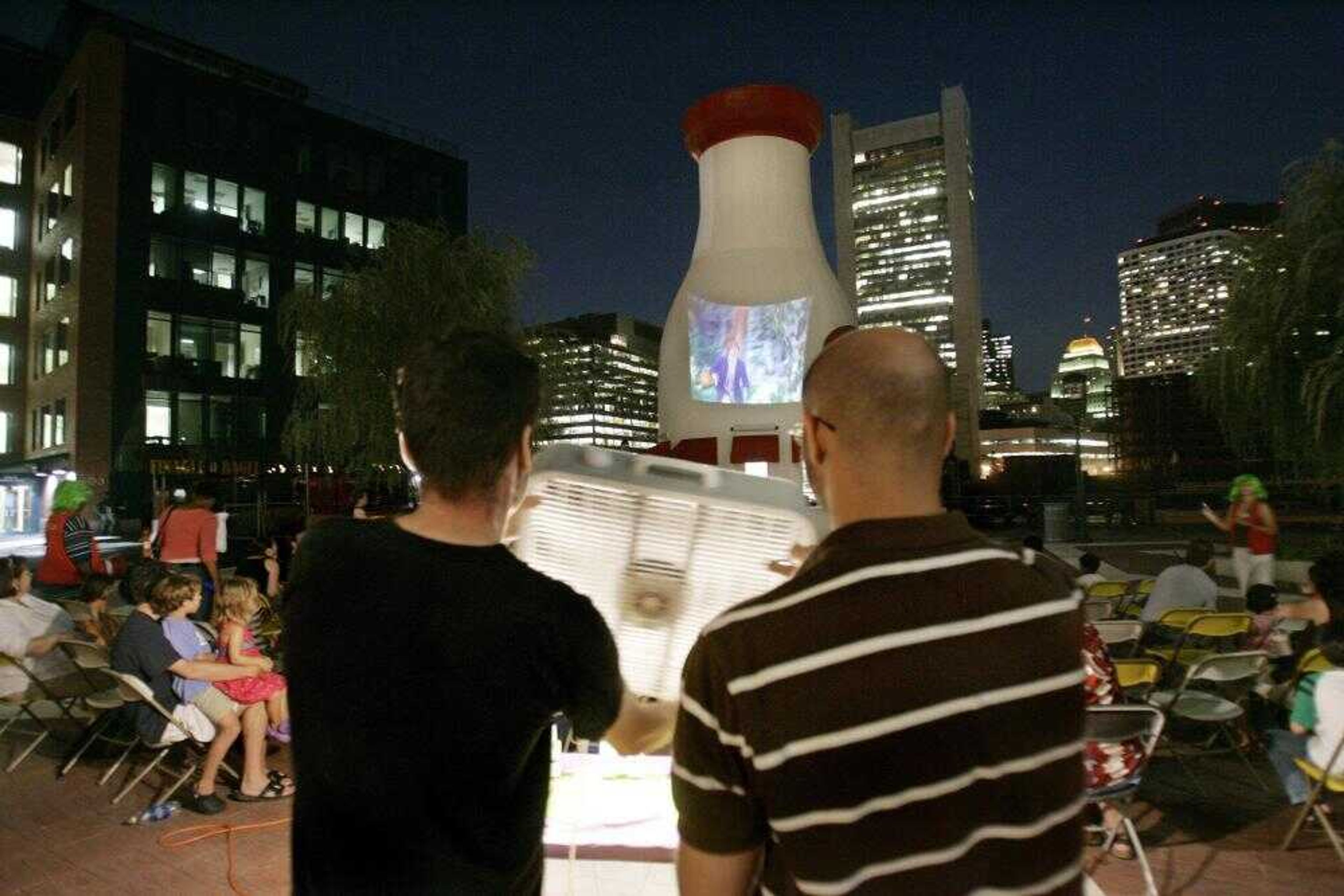 Mike Piso, left, and Children's Museum Curator of Movies, JB Sapienza, held a box fan to blow a mist of scented oils toward the audience Aug. 24 during a showing of "Willy Wonka and the Chocolate Factory" in "Smellovision" outside the Children's Museum in Boston. (Charles Krupa ~ Associated Press)