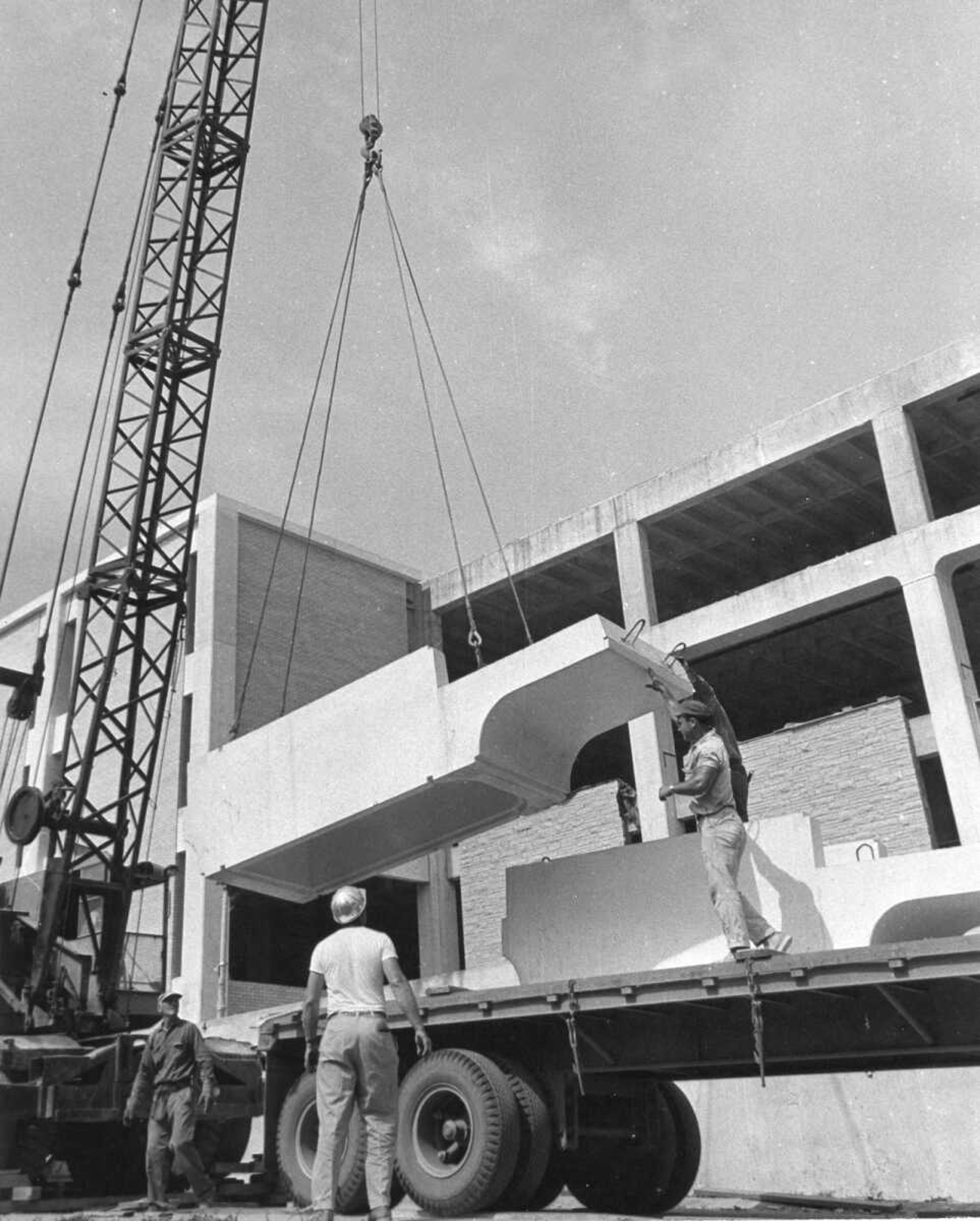 Published June 13, 1967
Workmen unload one of the huge 6-ton precast concrete units that will make up the coping along the front and sides leading to the front of the expanded Kent Library at State College. There will be 96 of these units in the finished building, the group weighing 576 tons. Only three of the blocks can be hauled on a truck at a time because of their weight, and drivers for the Wilson Concrete Co., which precast the units, say they will have to make 32 truck trips between here and Omaha, Nebraska, to complete the delivery. (Southeast Missourian archive photo)