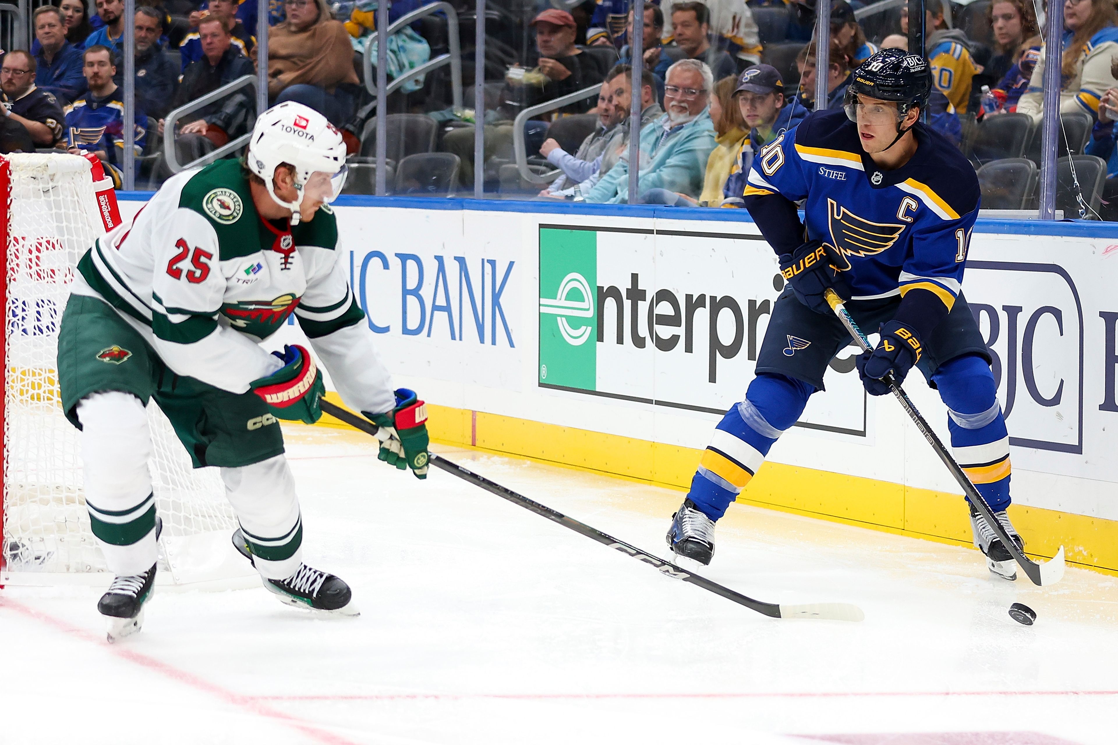 St. Louis Blues' Brayden Schenn (10) handles the puck as Minnesota Wild's Jonas Brodin (25) defends during the second period of an NHL hockey game Tuesday, October 15, 2024, in St. Louis. (AP Photo/Scott Kane)