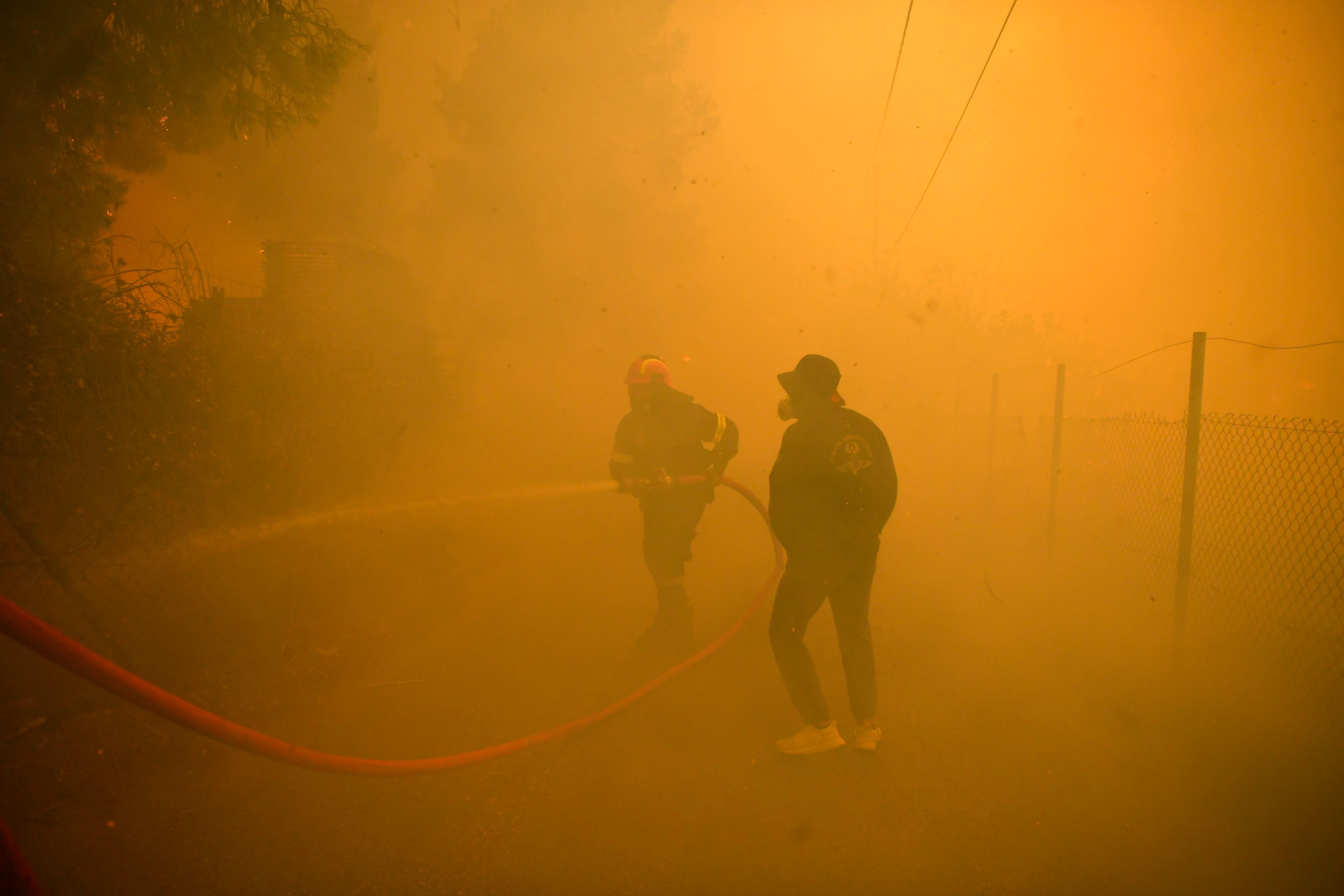 FILE - A firefighter and volunteer try to extinguish a wildfire in northern Athens, Aug. 12, 2024, as firefighters tackle a wildfire. (AP Photo/Michael Varaklas, File)