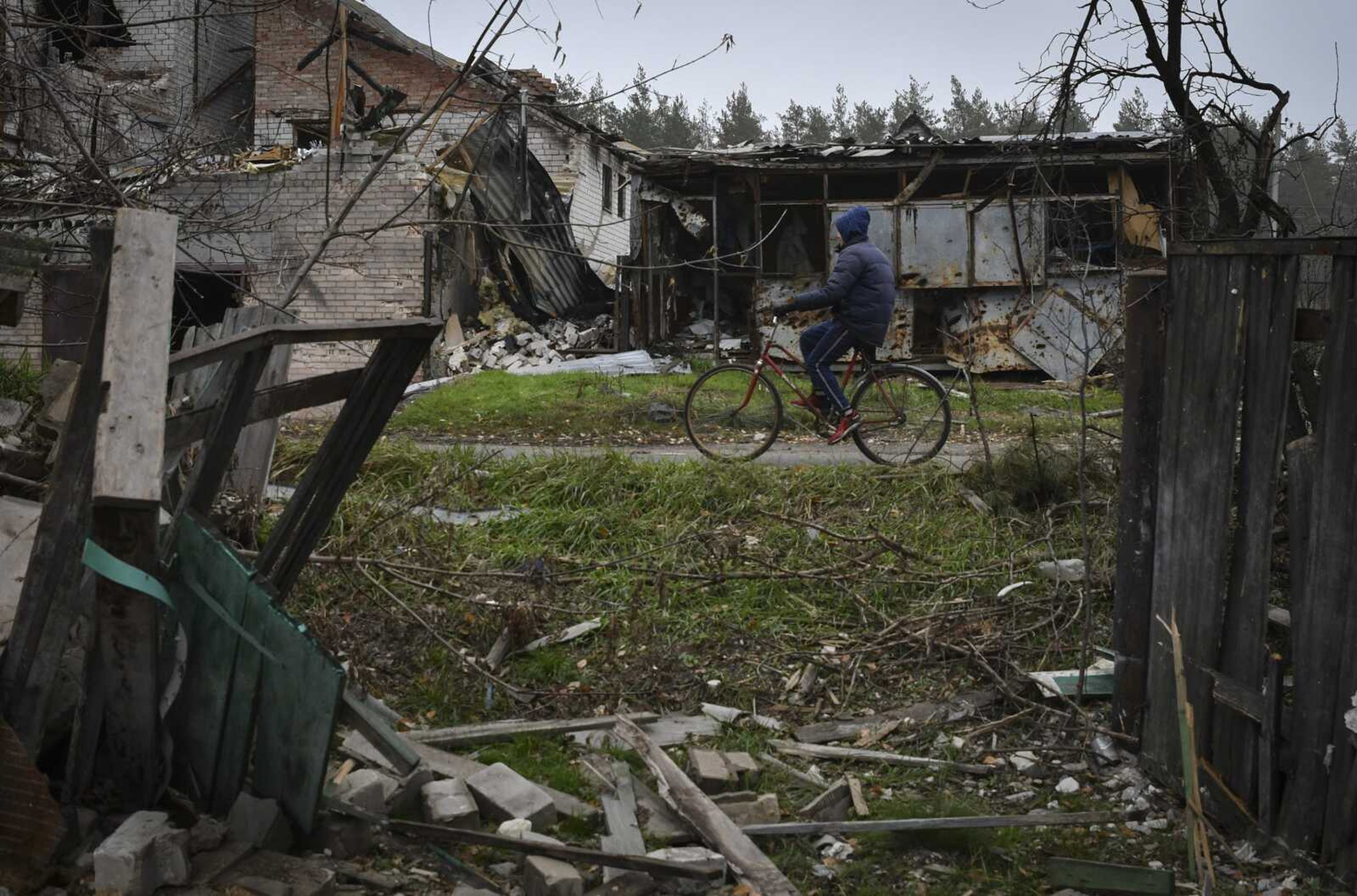 A woman rides a bicycle Wednesday past destroyed buildings in the recently recaptured village of Yampil, Ukraine. Villages and towns in Ukraine saw more heavy fighting and shelling Wednesday as Ukrainian and Russian forces strained to advance on different fronts after more than 8   months of war.