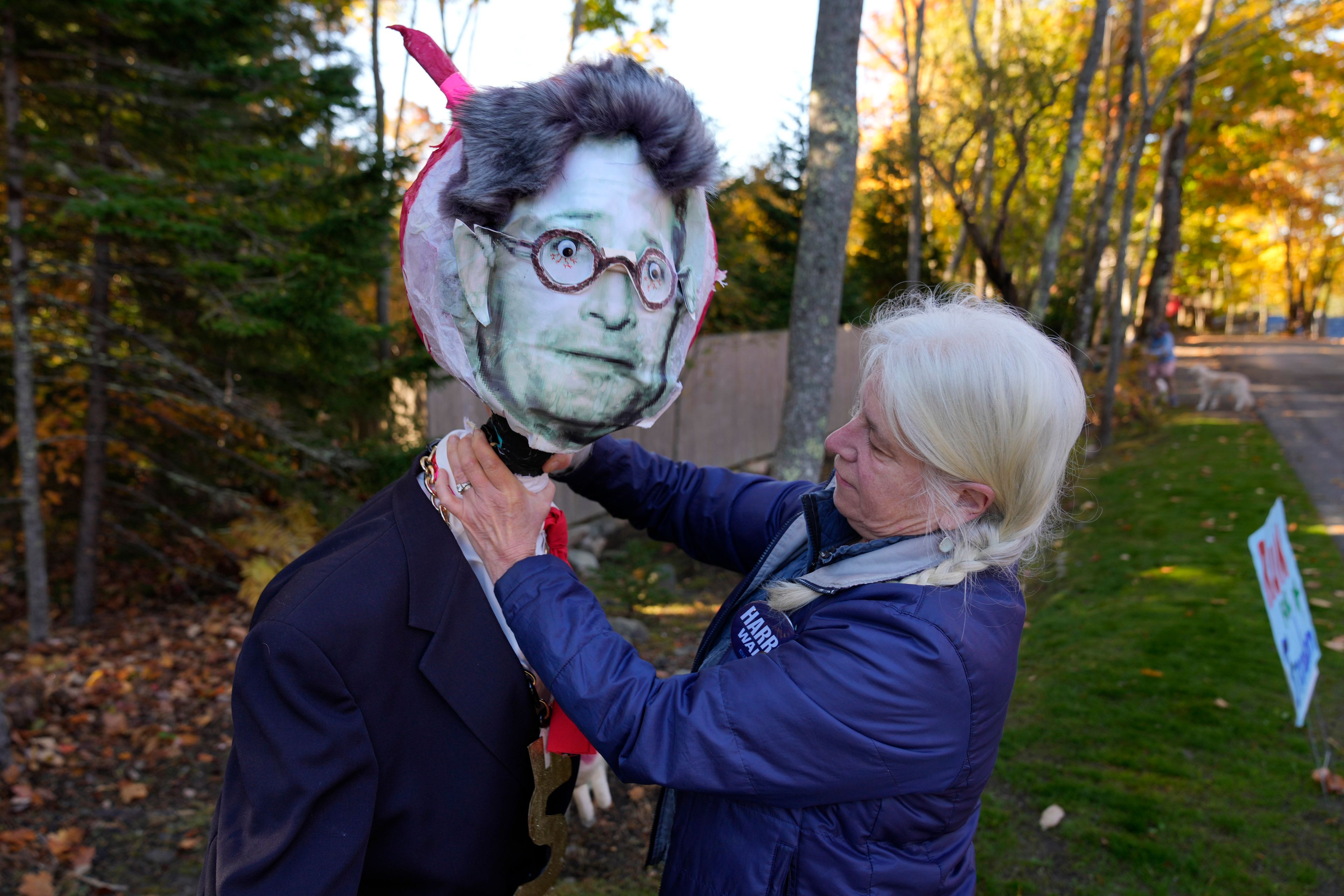 Caroline Pryor adjusts the head of a mannequin bearing an image of Leonard Leo during a protest, Sunday, Oct. 20, 2024, in Northeast Harbor, Maine. (AP Photo/Robert F. Bukaty)