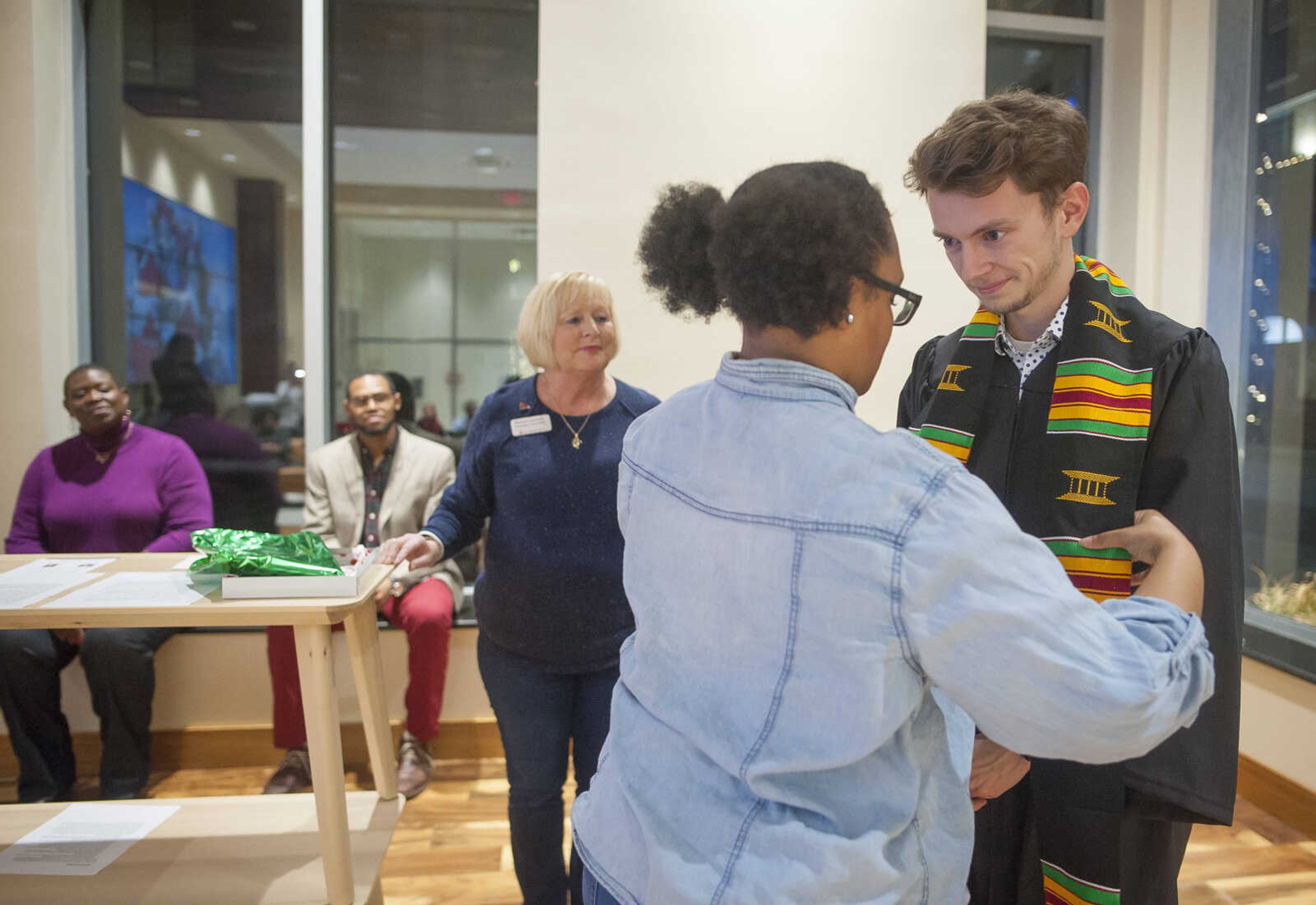 Makayla Caldwell, secretary of the National Association of Black Journalists at Southeast Missouri State University, adorns Alex Bargen, right, with his Kente stole during the inaugural "Donning of the Kente" ceremony Monday, Dec. 9, 2019, at Rust Center for Media, which recognized graduating NABJ members in Cape Girardeau.