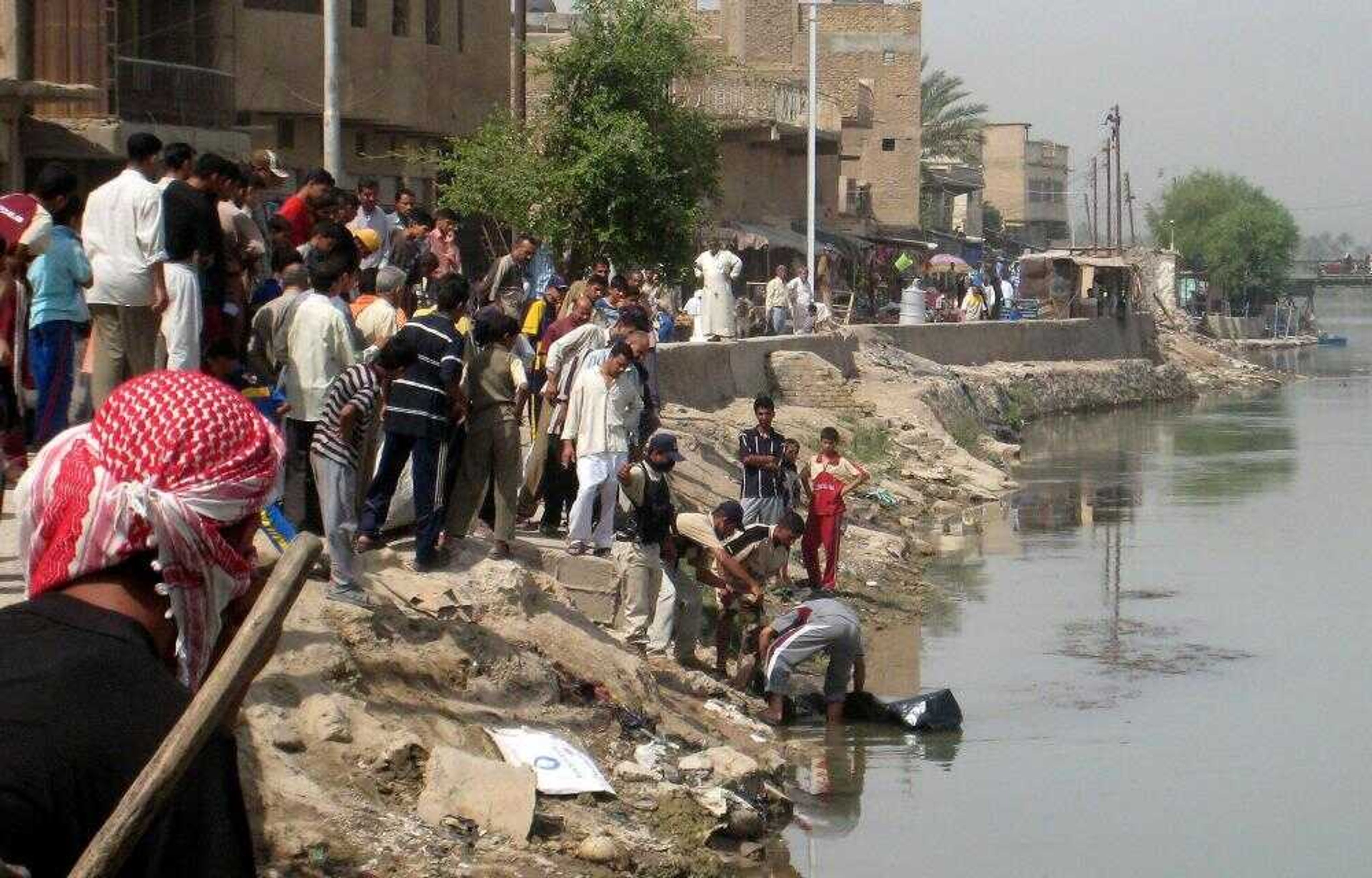 Iraqi men and a policeman try to pull a body from the Euphrates river in southern Baghdad, Iraq, on Wednesday. Police in the south of Baghdad found a body floating in the Euphrates River that they say is one of three American soldiers abducted by al-Qaida nearly two weeks ago. (Associated Press)