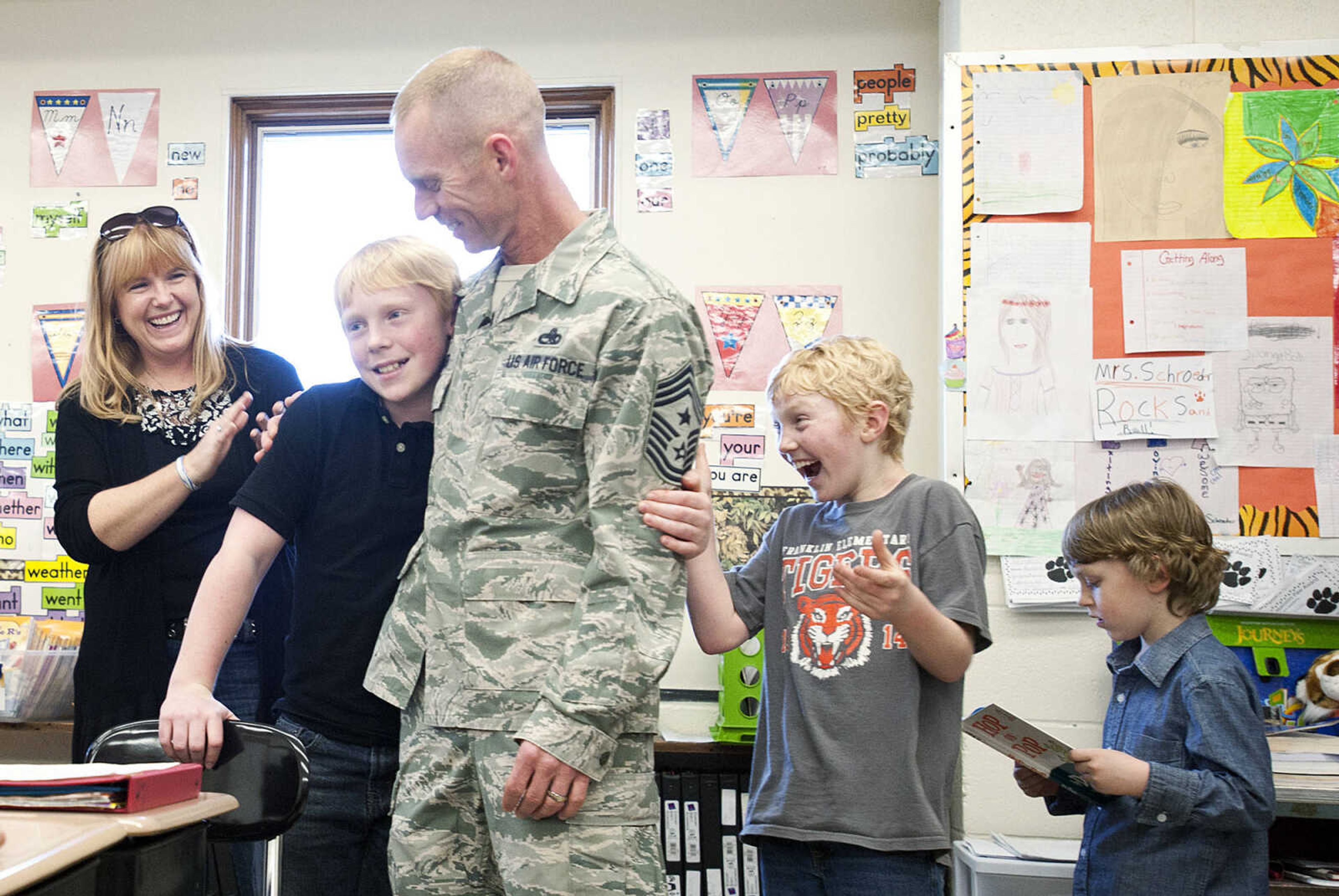 Geordan Weimer, 11, hugs his father Command Chief Master Sgt. Geoff Weimer as his mother LeAnne Weimer, left, and bothers Eli, 9, and Gabriel, 6, right, look on  Friday, March 14, at Central Middle School in Cape Girardeau. Sgt. Weimer is on leave from the Air Force after being deployed in the Middle East since Oct., and surprised his three sons, Geordan, 11, Eli, 9, and Gabriel, 6, in their respective classes.