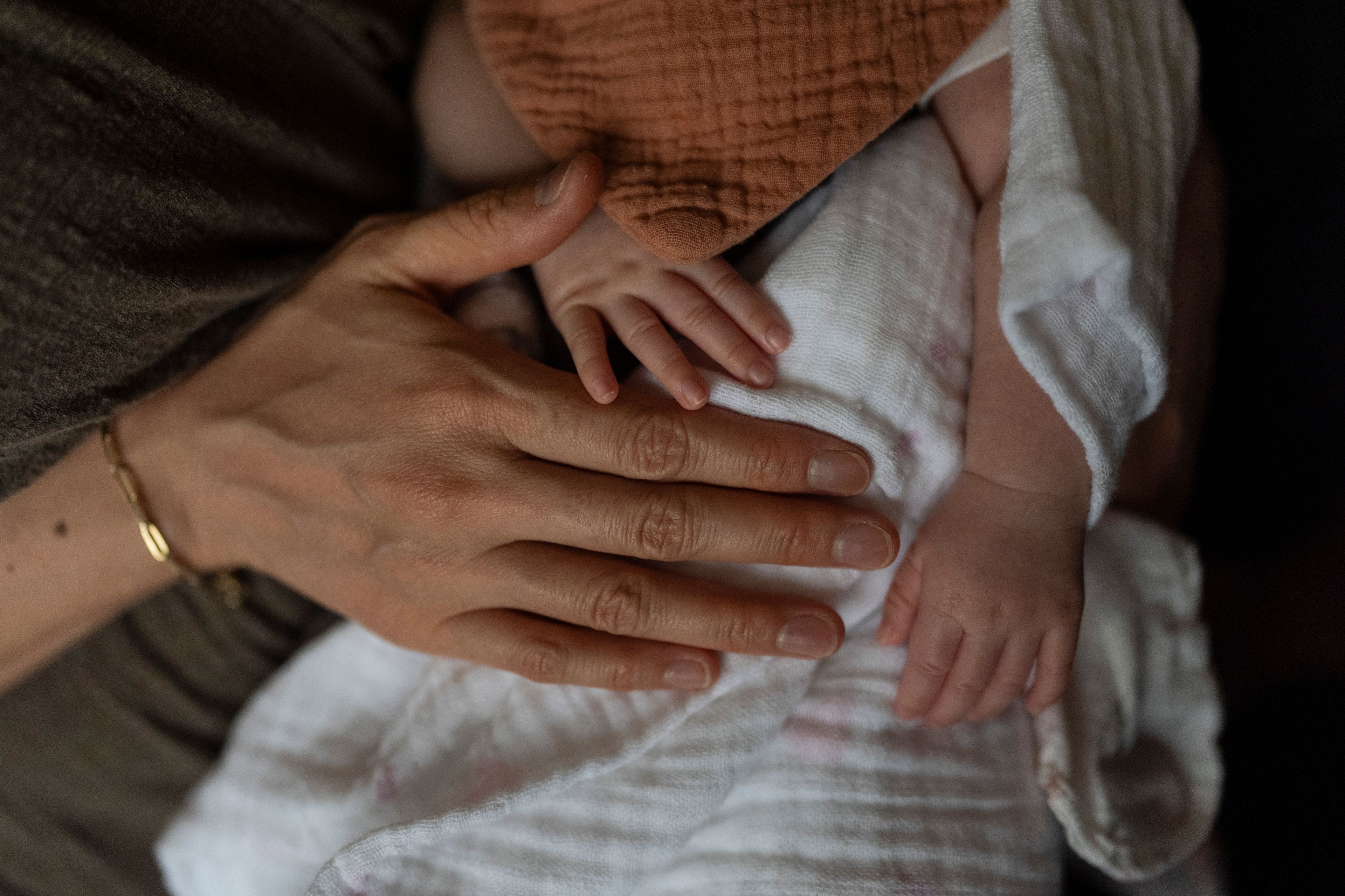 Robyn Joy Park, an adoptee from South Korea, gently pats her newborn daughter, Rae, at her home in Pasadena, Calif., Friday, April 19, 2024. (AP Photo/Jae C. Hong)