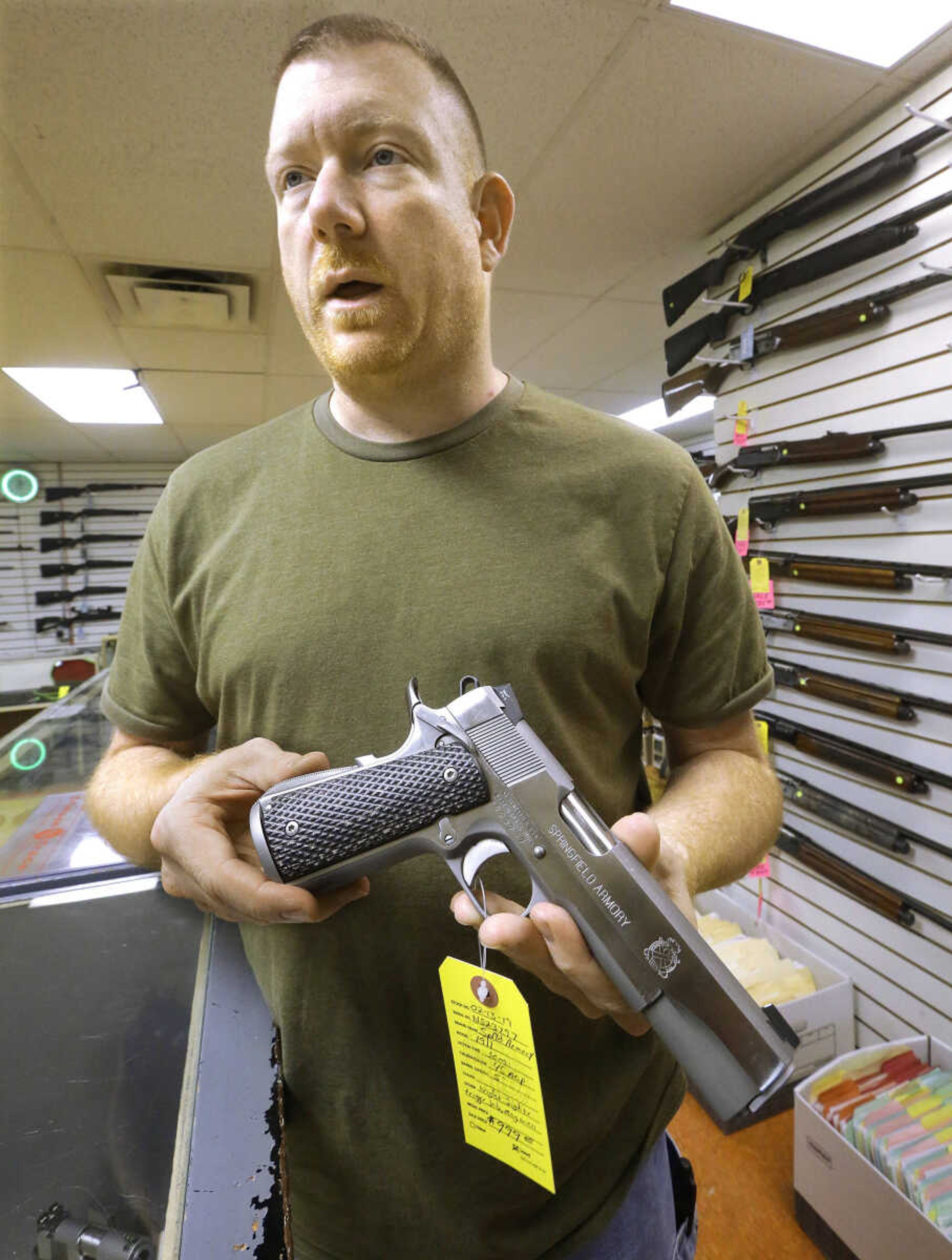 John Jackson, owner of Capitol City Arms Supply in Springfield, Ill., holds a handgun at his business Wednesday, July 10, 2013. Jackson says his business has spiked since the federal appeals court late last year tossed out Illinois' concealed-carry ban, and his phone has been ringing off the hook with calls from customers wanting to make use of his shop's indoor shooting range and related training. Months of debate about Illinois' last-in-the-nation ban on concealed carry came to an end when lawmakers narrowly beat a federal court deadline and adopted a carry law over Illinois Gov. Pat Quinn's objections, shifting the focus to how to carry out the new law across the state's 102 counties. (AP Photo/Seth Perlman)