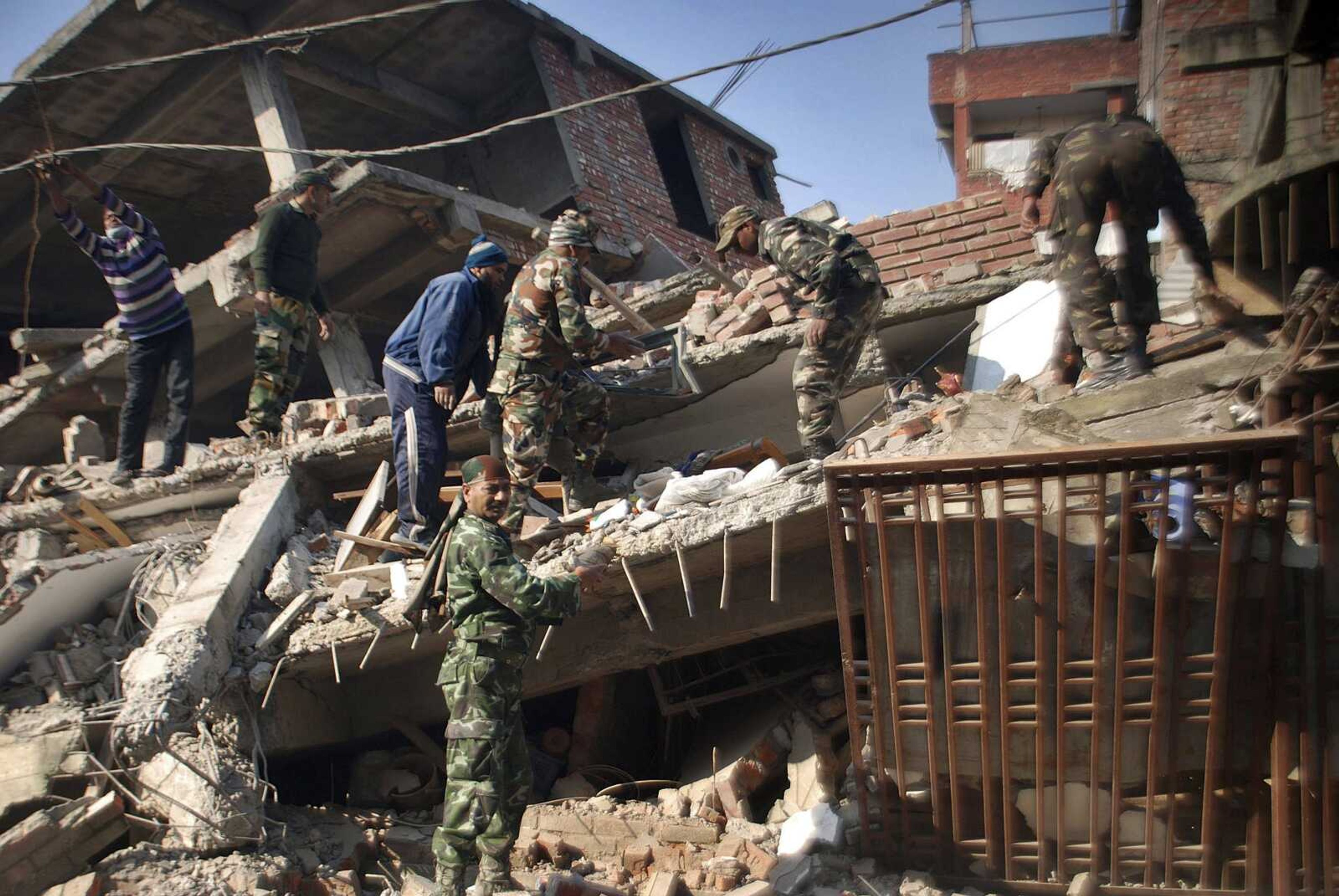 Indian soldiers and locals remove debris from a damaged building after an earthquake Monday in Imphal, India. (Bullu Raj ~ Associated Press)