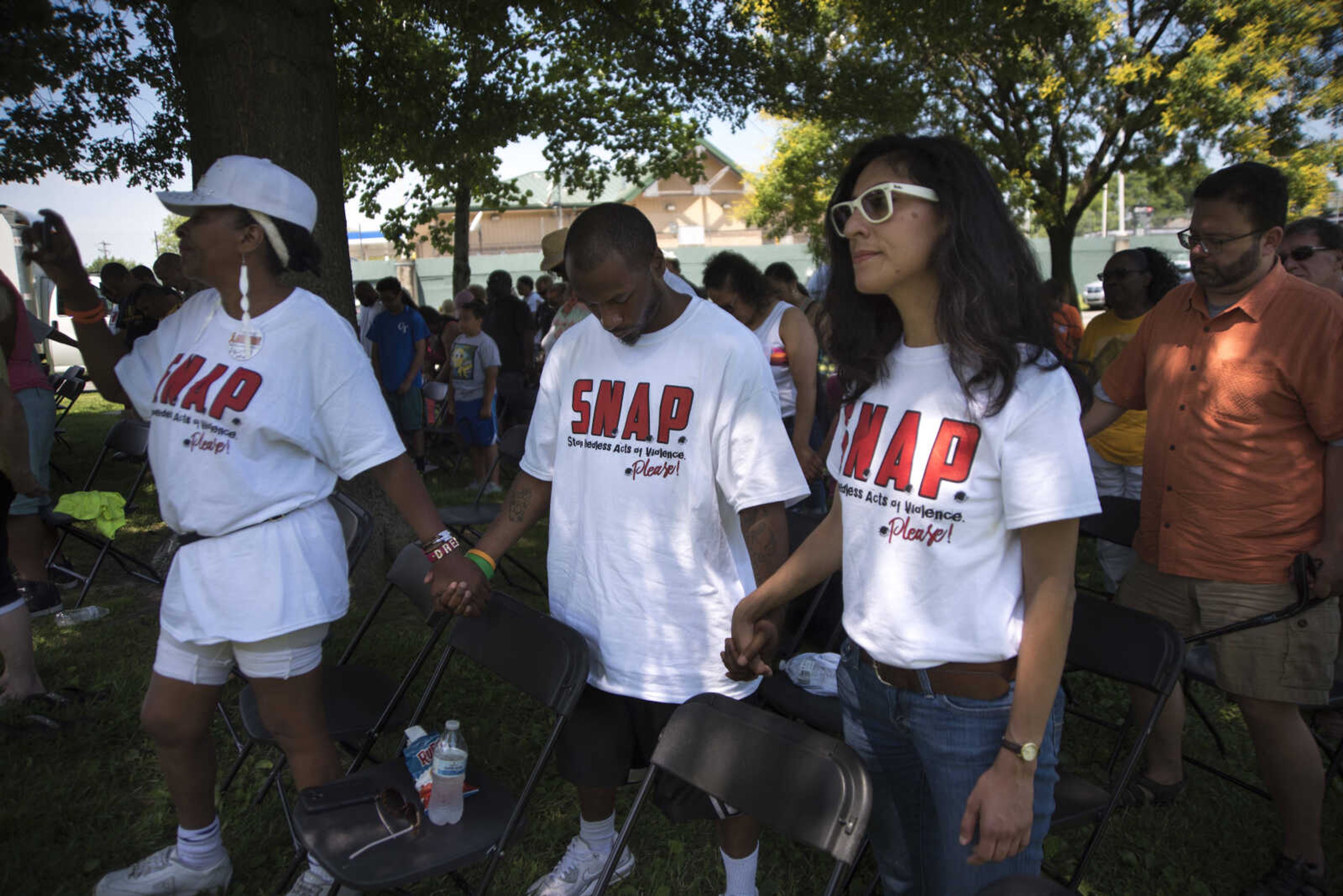 Community members hold hands at Ranney Park during a Stop Needless Acts of Violence Please (SNAP) prayer march Saturday, June 10, 2017 in Cape Girardeau.