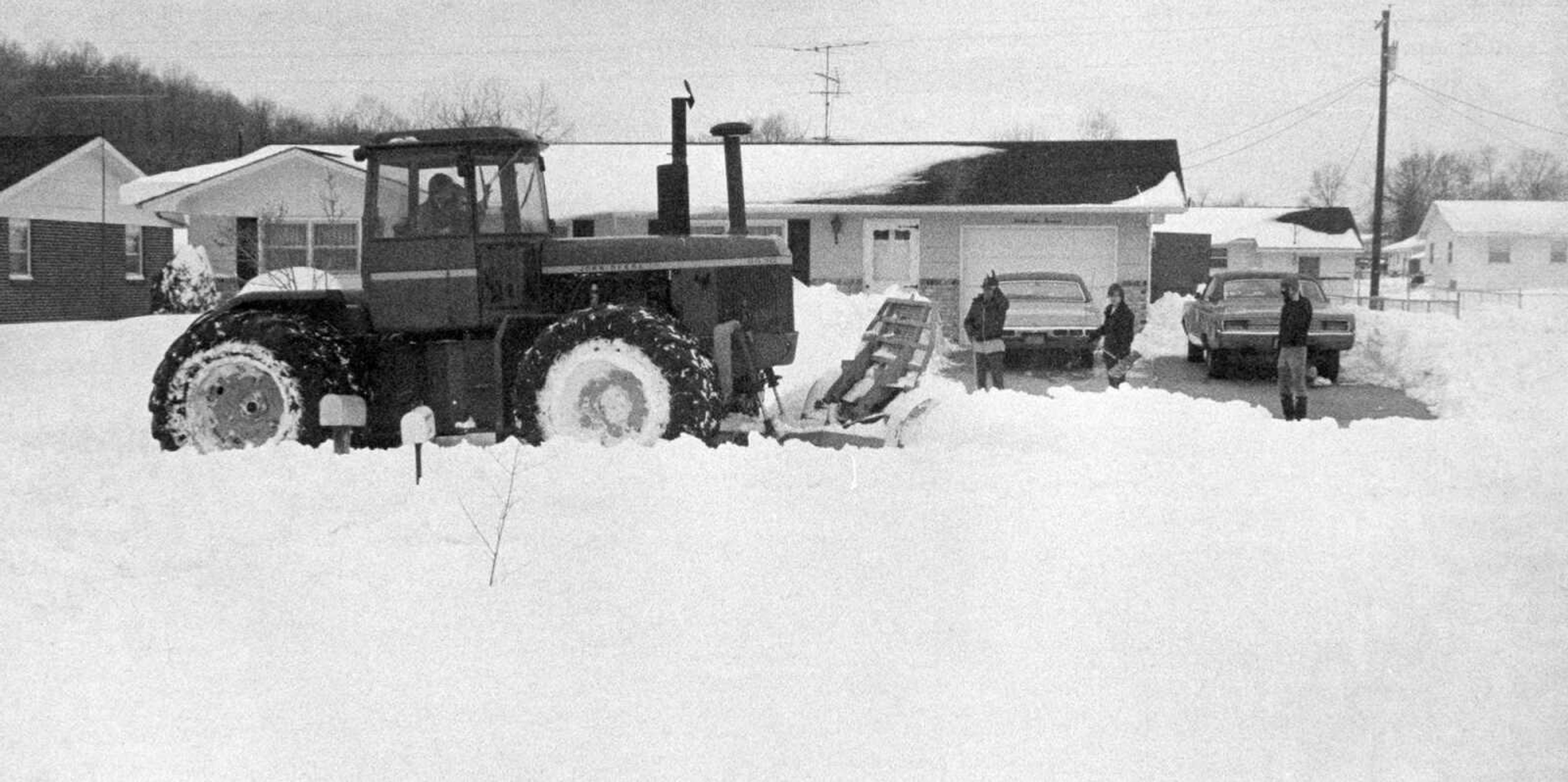 Two unidentified men in a John Deere tractor with a blade attachment helped clear a residential street. (Southeast Missourian archive photo)