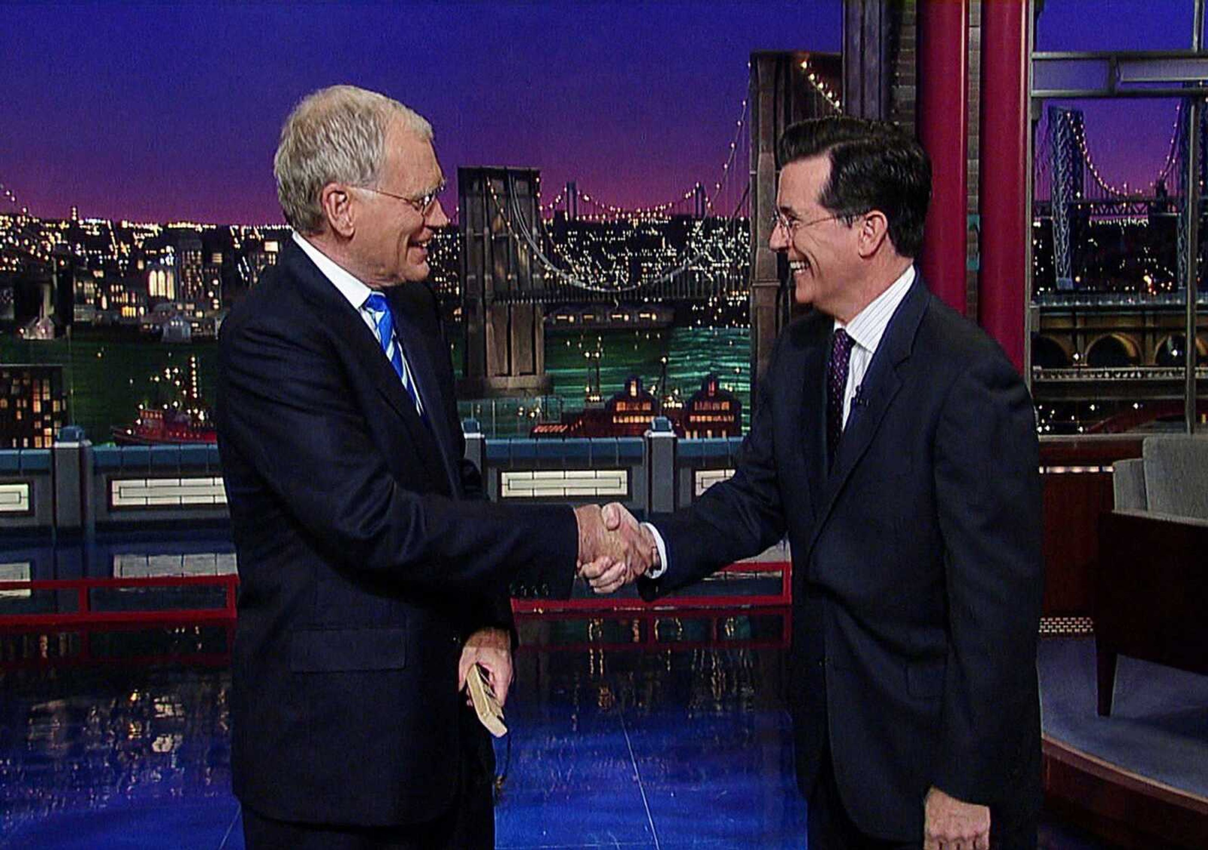 David Letterman, left, shakes hands with fellow talk show host Stephen Colbert of &#8220;The Colbert Report&#8221; during a surprise visit in May 2011 on the &#8220;Late Show with David Letterman&#8221; in New York. CBS on Thursday announced Colbert will succeed Letterman as the host of &#8220;The Late Show.&#8221; (CBS, Worldwide Pants Inc. ~ AP)