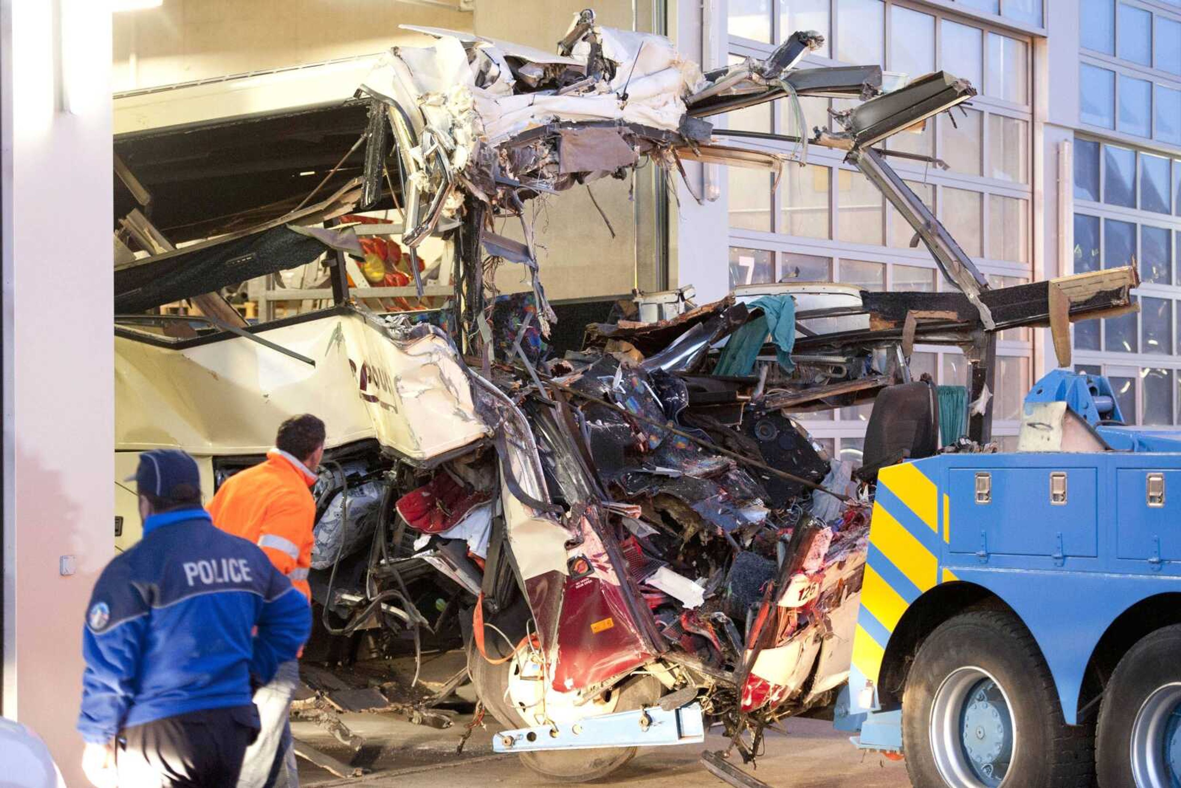 The wreckage of a tourist bus from Belgium is dragged by a tow truck outside the tunnel of the motorway A9, in Sierre, Switzerland, early Wednesday. (Laurent Gillieron ~ Keystone)