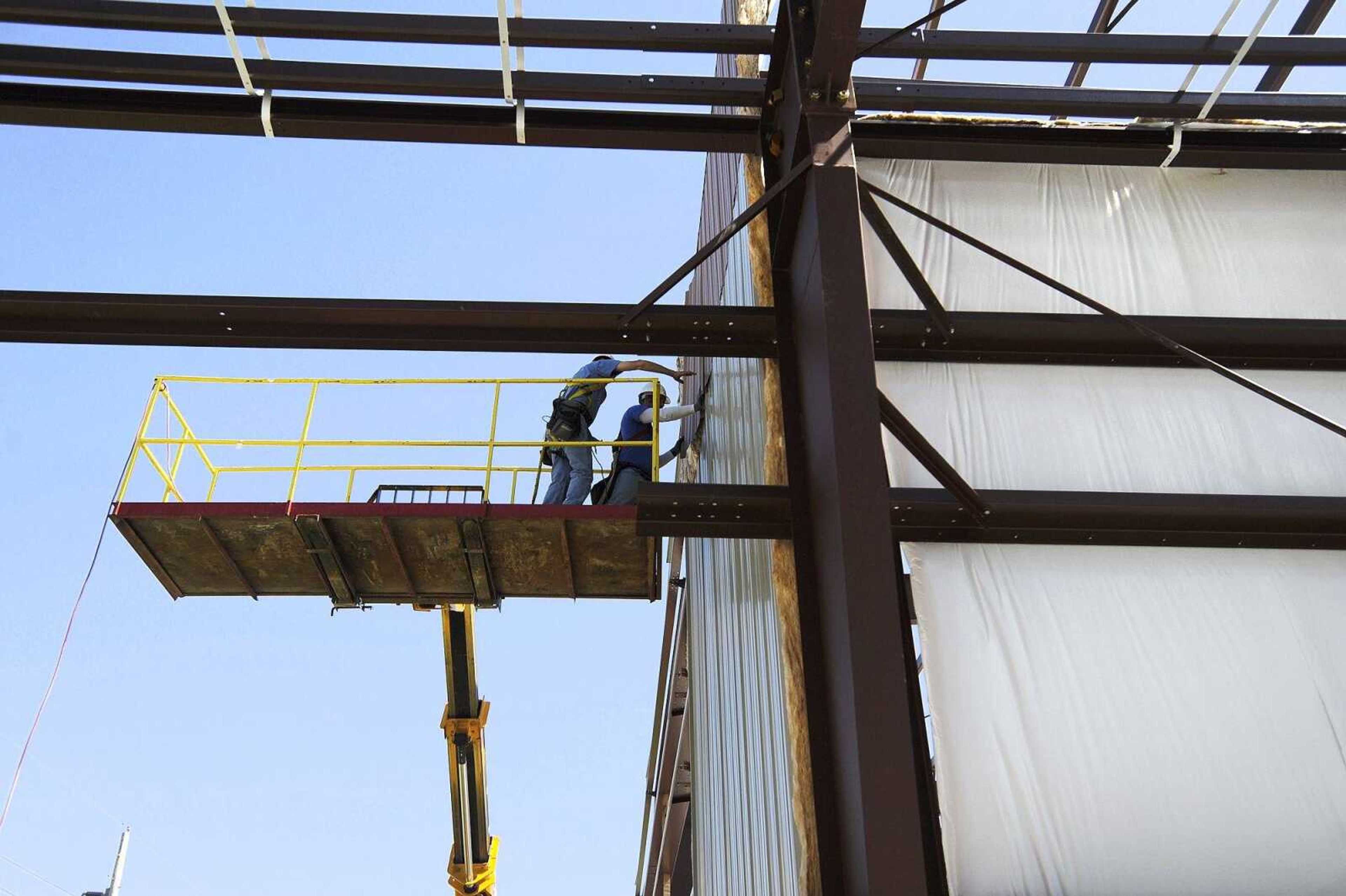 Rob Deimond, left, and Curtis Holt of Scroggins Construction, secure siding on an exterior wall Monday of the new building expansion at Kohlfield Distributing Inc. in Cape Girardeau.