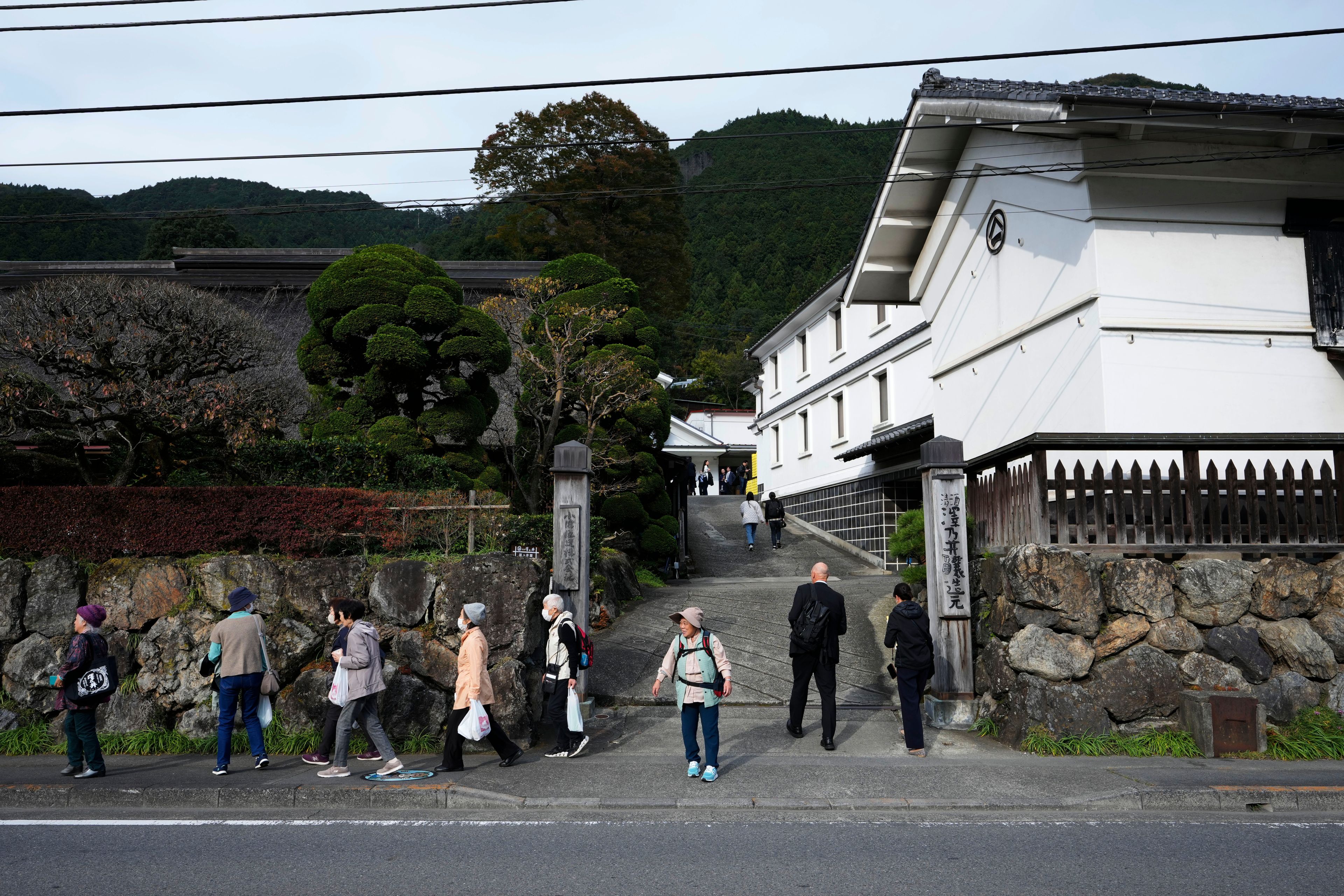 Visitors of Ozawa Sake Brewery leave as journalists enter the brewery on a media tour in Ome, on the western outskirts of Tokyo, Japan, Wednesday, Nov. 13, 2024. (AP Photo/Hiro Komae)