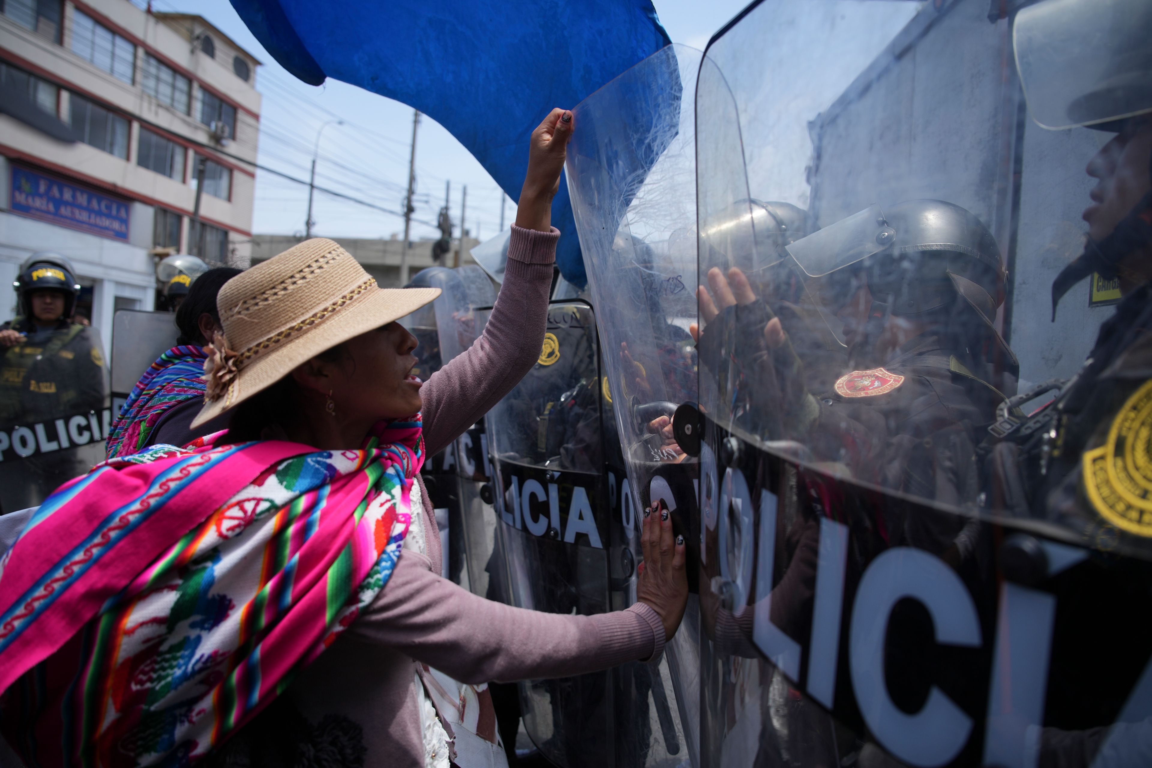 An anti-government protester pushes the shield of a police officer during a demonstration on the sidelines of the Asia-Pacific Economic Cooperation (APEC) summit in Lima, Peru, Friday, Nov. 15, 2024. (AP Photo/Guadalupe Pardo)