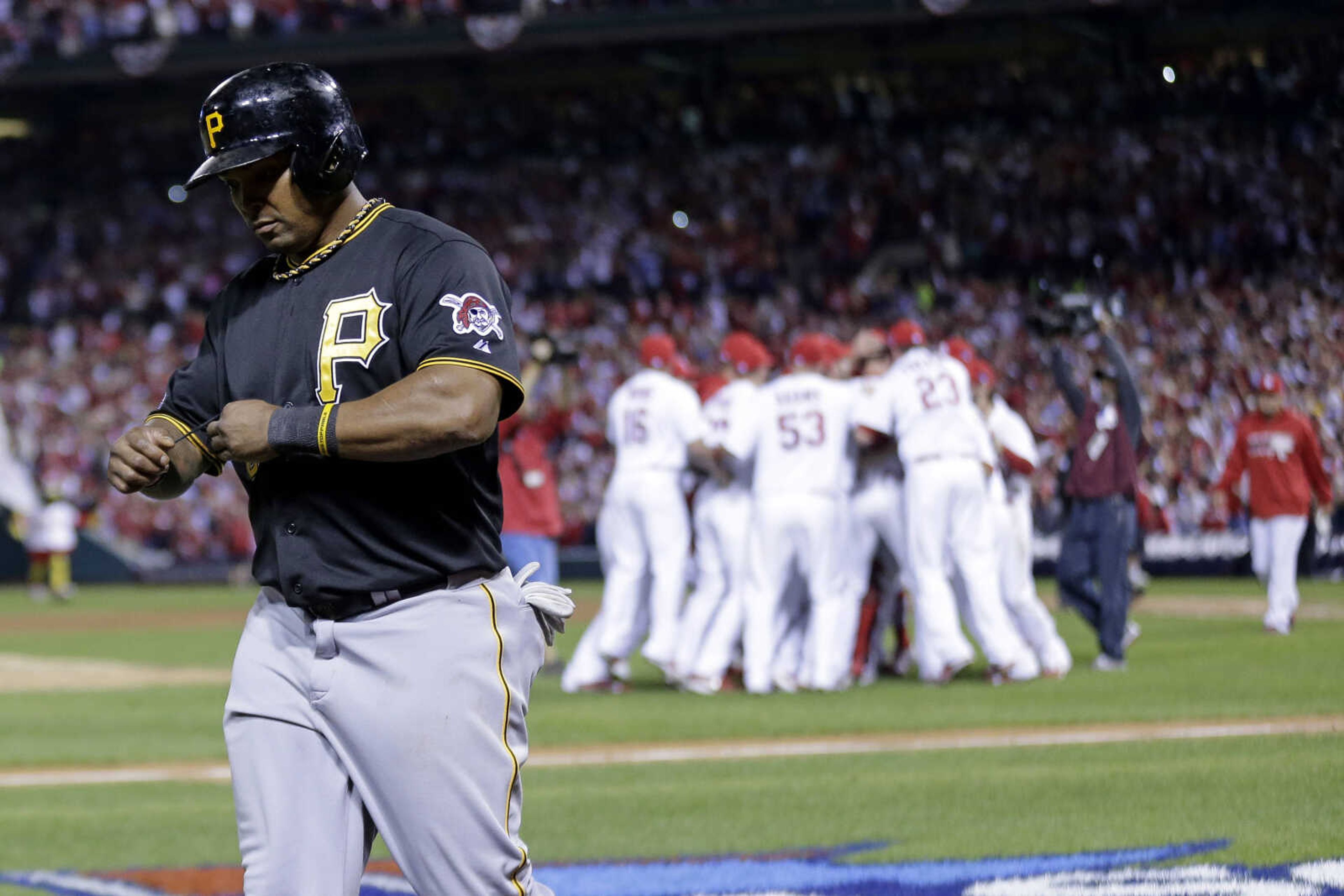 Pittsburgh Pirates' Marlon Byrd, left, walks off the field as the St. Louis Cardinals celebrate after the Cardinals beat the Pirates 6-1 to win Game 5 of a National League baseball division series on Thursday, Oct. 10, 2013, in St. Louis. (AP Photo/Charlie Riedel)