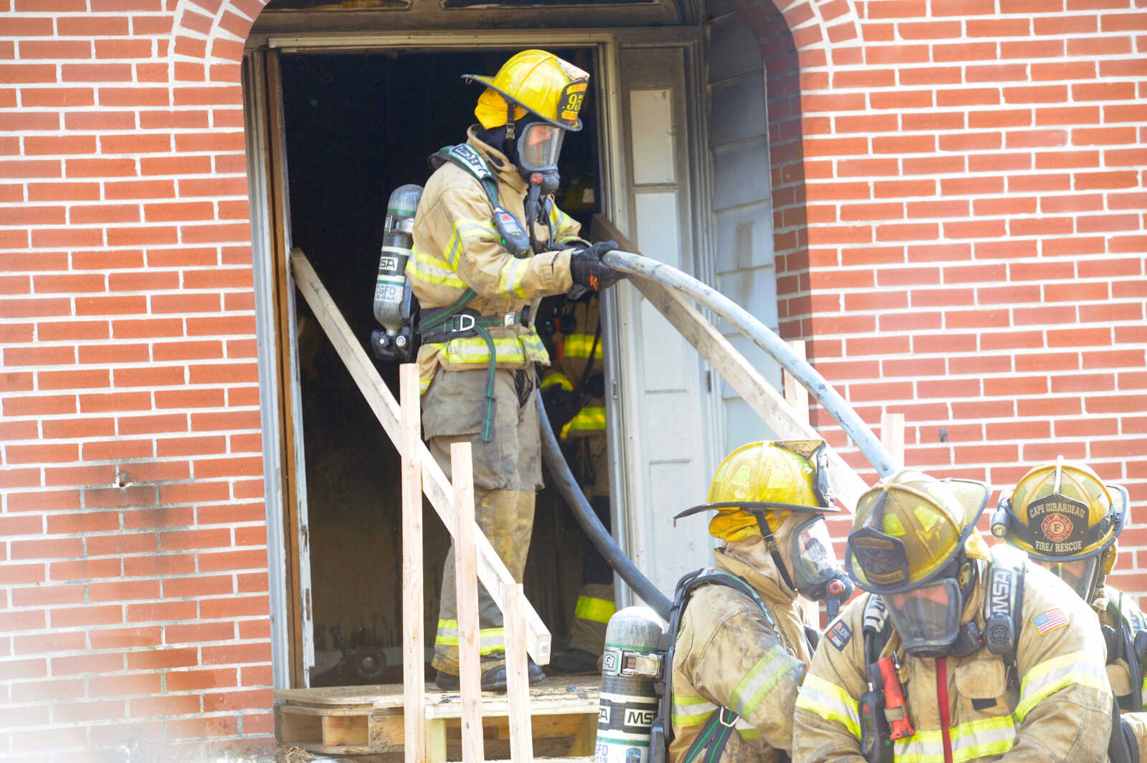 First- and second-year firefighters feed the hose to members inside at the live burn exercise at 222 N. Middle St. in Cape Girardeau on Friday, Oct. 23, 2020, held by the Cape Girardeau Fire Department.&nbsp;