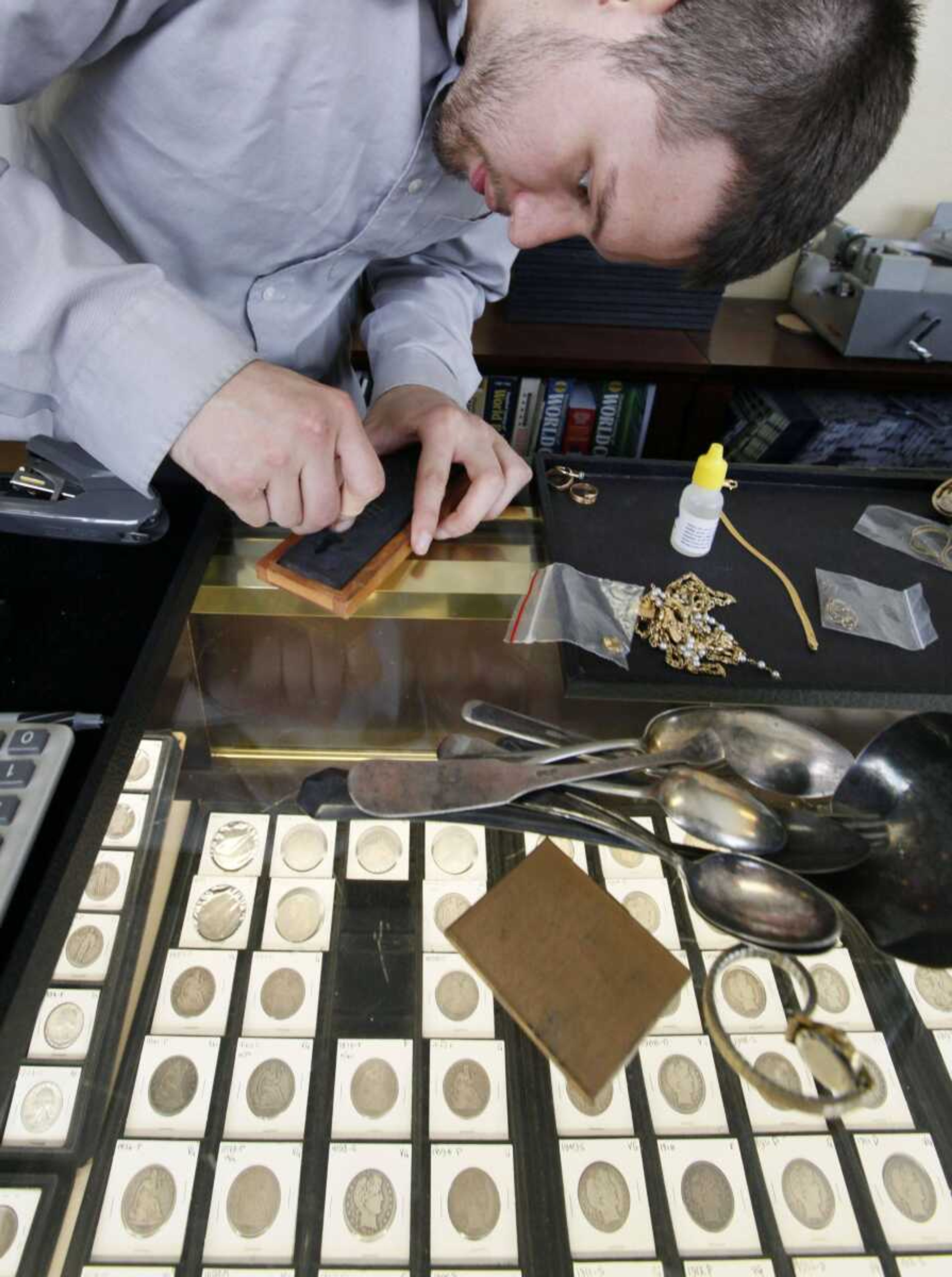 Davis Hardgrove performs a &#8220;scratch test&#8221; July 27 on a piece of gold jewelry that a customer brought in to sell at a coin shop in Seattle. Gold traded at $1,788 an ounce Tuesday, up 26 percent this year. (Elaine Thompson ~ Associated Press)