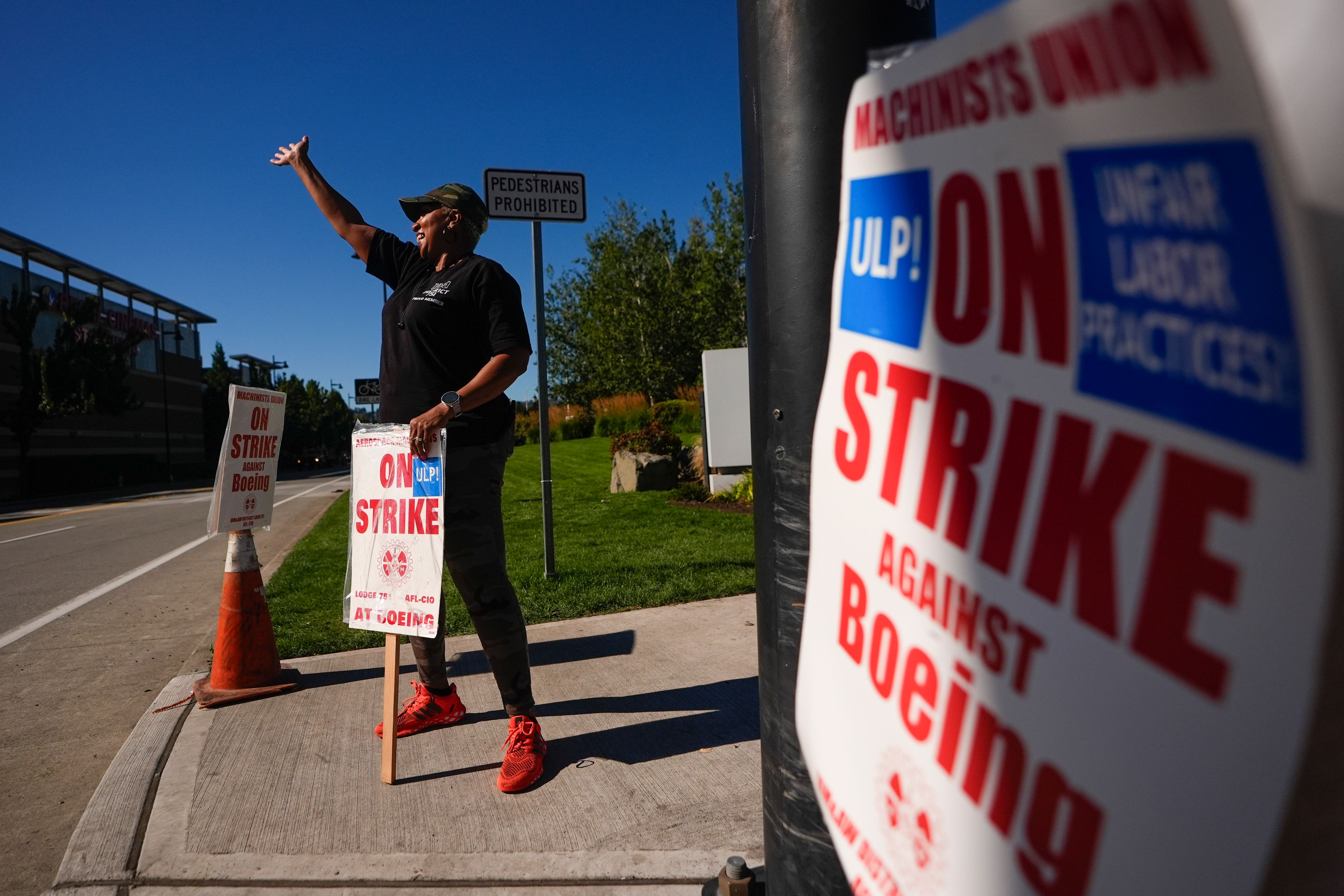 Toni Bailey, who has worked at Boeing for 40 years, waves at passing drivers while working the picket line as union members continue to strike Tuesday, Sept. 24, 2024, near the company's factory in Renton, Wash. (AP Photo/Lindsey Wasson)