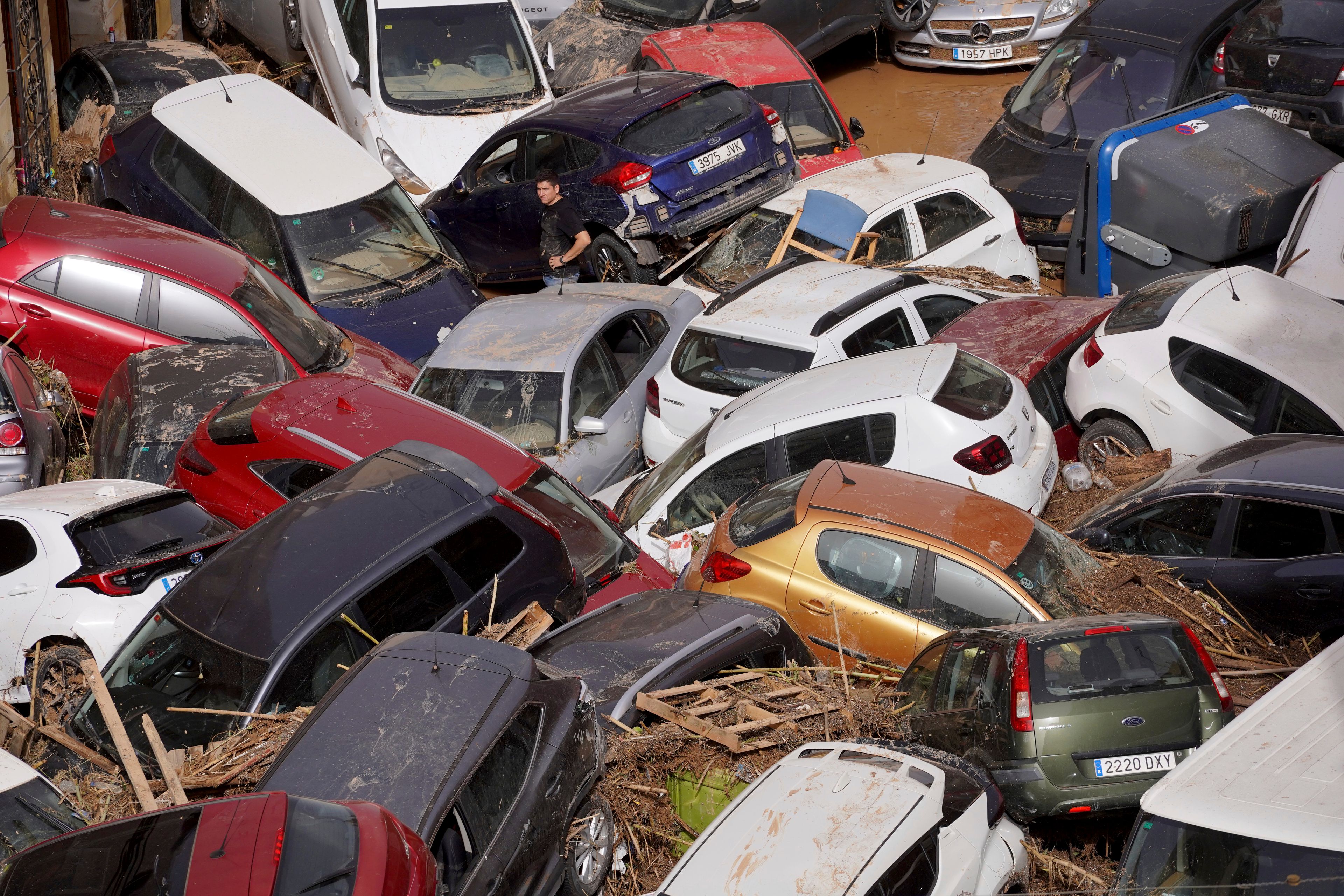 Residents look at cars piled up after being swept away by floods in Valencia, Spain, Wednesday, Oct. 30, 2024. (AP Photo/Alberto Saiz)