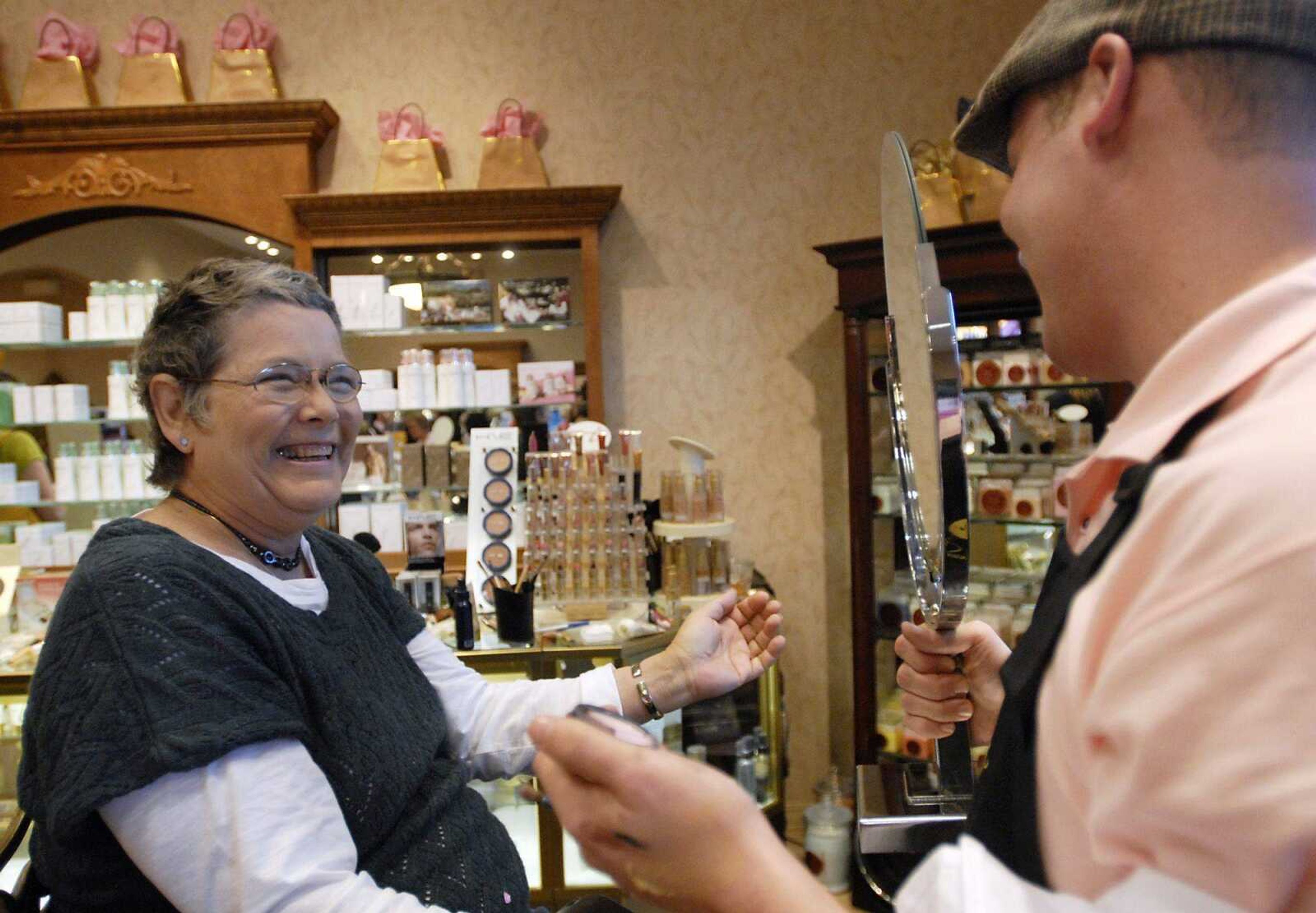 Valerie Williams reacts Thursday as Belladona employee John Paul Long holds a mirror for her to see her makeover results during the Rise Above with Love event. Williams' was diagnosed with breast cancer about a year ago, and has been in remission for four months. Belladona Salon partnered with Southeast Missouri Hospital for the event to promote breast cancer awareness, by providing free salon services for breast cancer survivors, giveaways, makeup demos and donating proceeds from the sale of a special lip gloss to Susan G. Komen for the Cure. (Kristin Eberts)