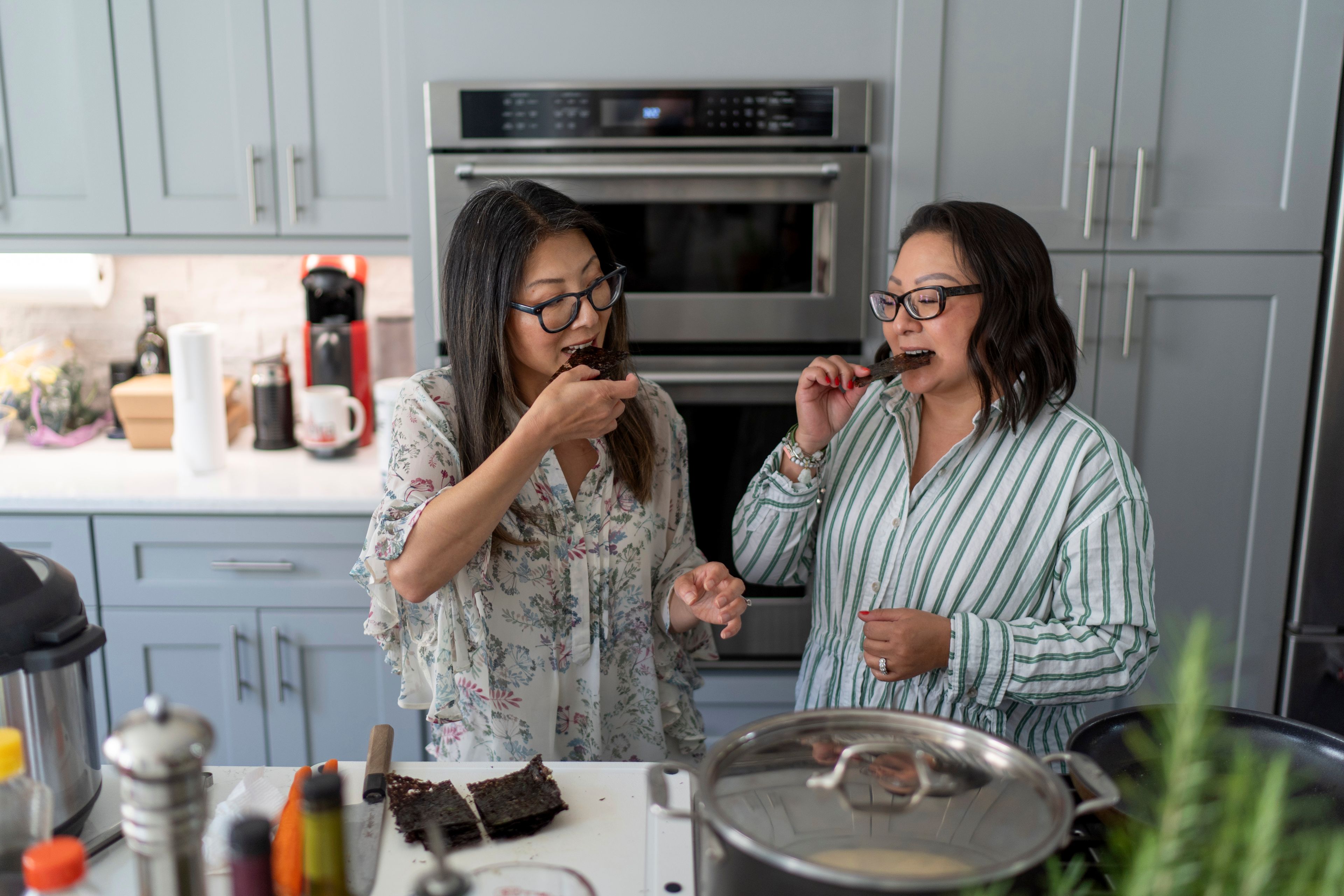 Dee Iraca, left, and Becca Webster, twins who were adopted out of South Korea to a family in the United States, try Korean-style roasted seaweed Iraca made at her home in Davidson, N.C., Saturday, April 6, 2024. The sisters always considered themselves very different which prompted them to take a DNA test in the first place; they wanted to confirm for themselves that they are biological sisters. The test result not only confirmed thy are twins, but eventually led them to their birth father. (AP Photo/David Goldman)