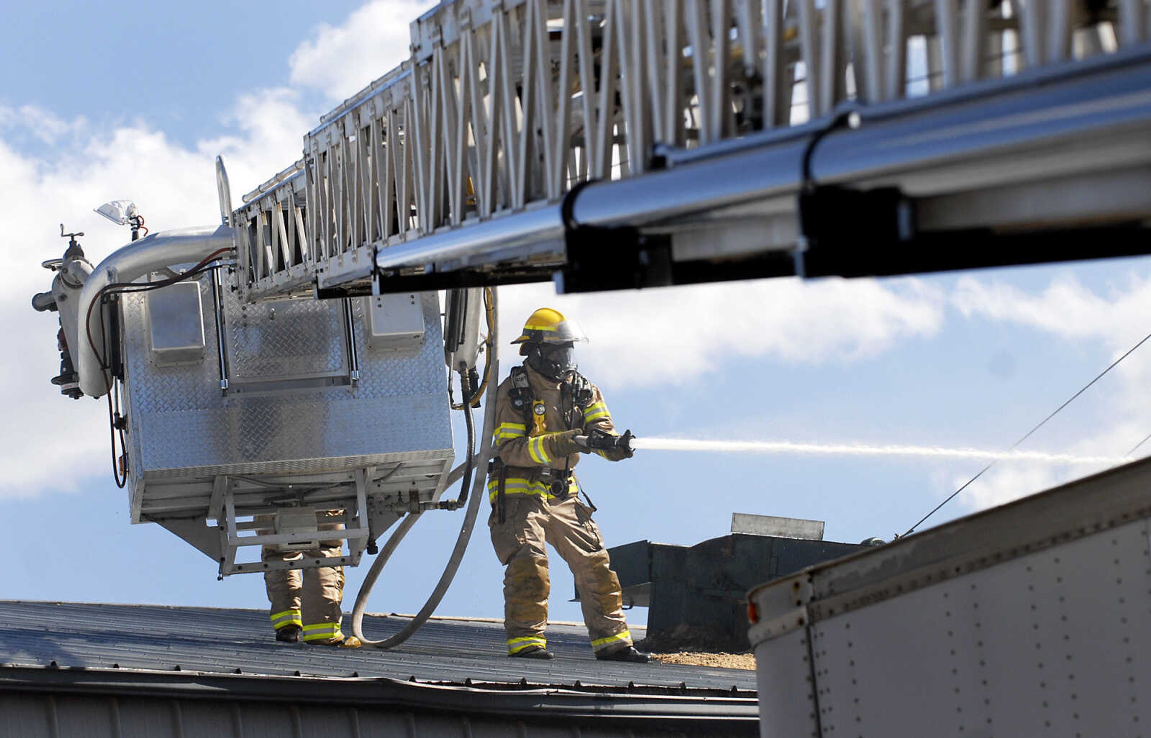 Jackson firefighter Justin Farrar controls a hose from the roof during a fire at Flickerwood Farms in Jackson on Wednesday, March 23, 2011. (Kristin Eberts)