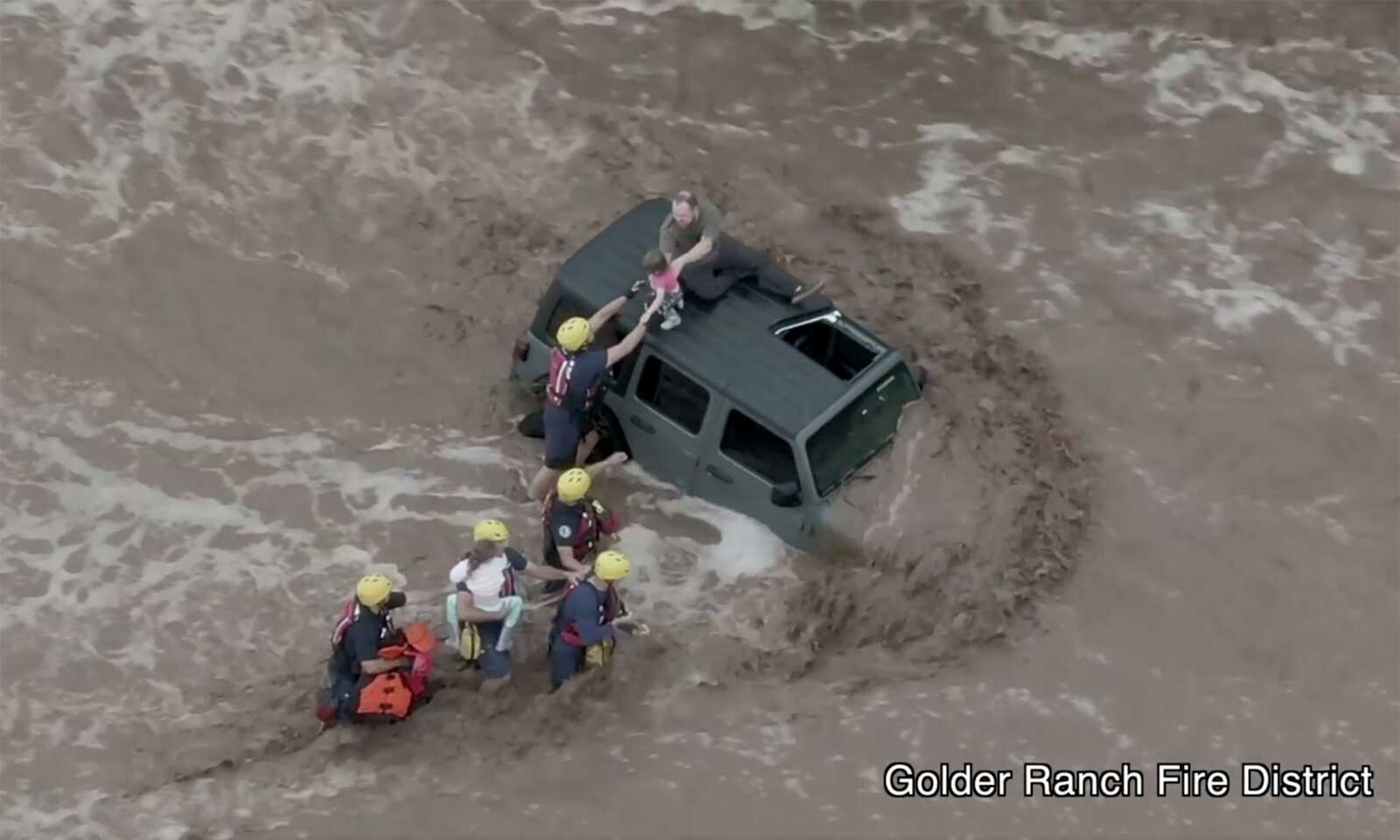 This drone image shows Firefighters safely rescue a man and his two daughters from the roof of their vehicle after it was swept away in fast moving water Wednesday just north of Tucson, Arizona.