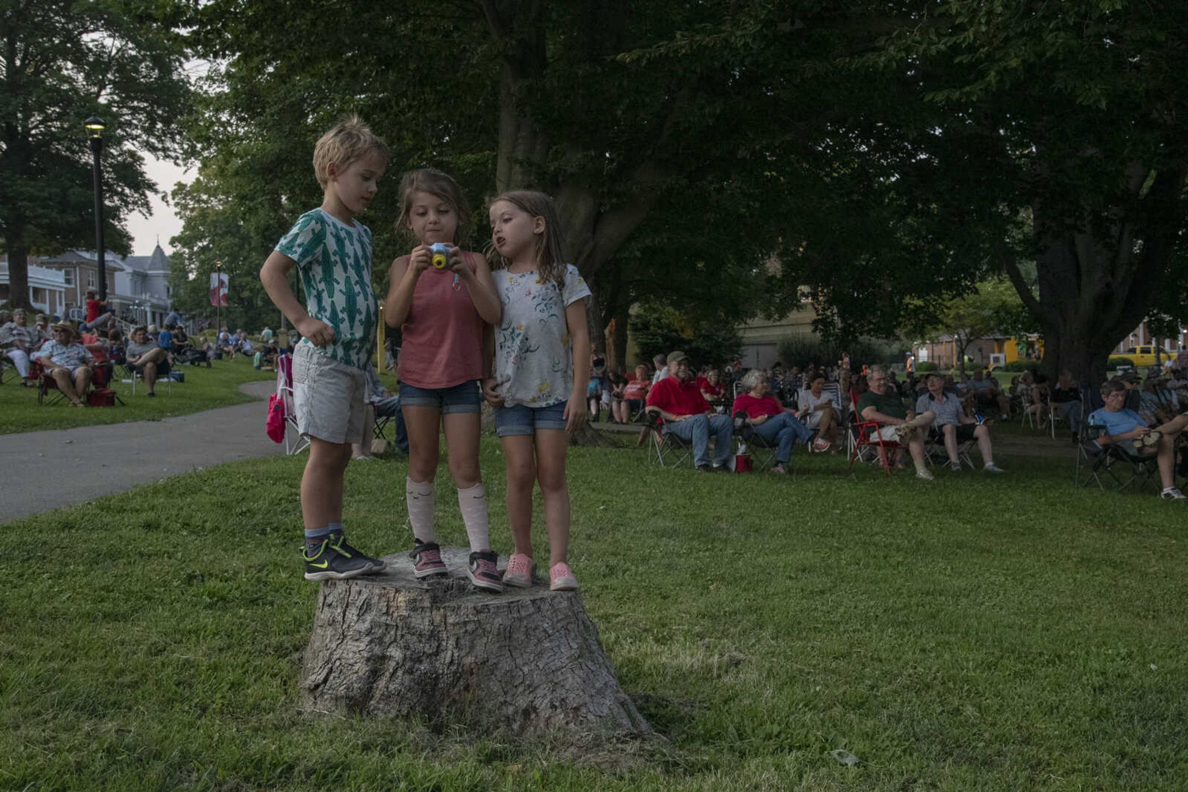 Charlie Dirnberger, 5, Lilly Carlton, 5, and Olive Carlton, 5, from left, look at the photos she just took with her camera during Tunes at Twilight at the River Campus Friday Aug. 6, 2021.