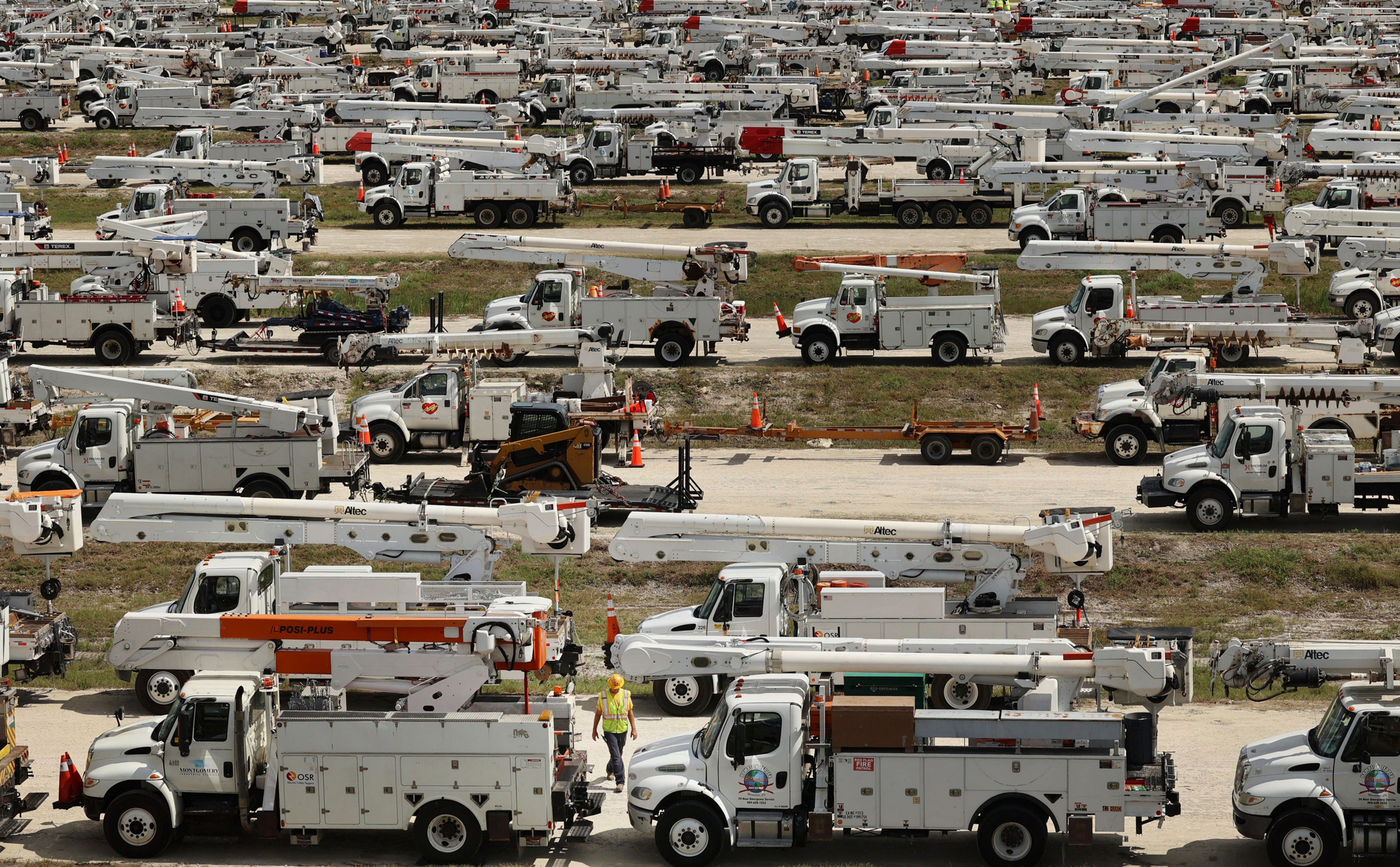 Duke Energy project manager Tiger Yates, bottom center, walks among the hundreds of lineman trucks staged, Tuesday, Oct. 8, 2024. at The Villages, Fla. in preparation for Hurricane Milton. (Stephen M. Dowell/Orlando Sentinel via AP)