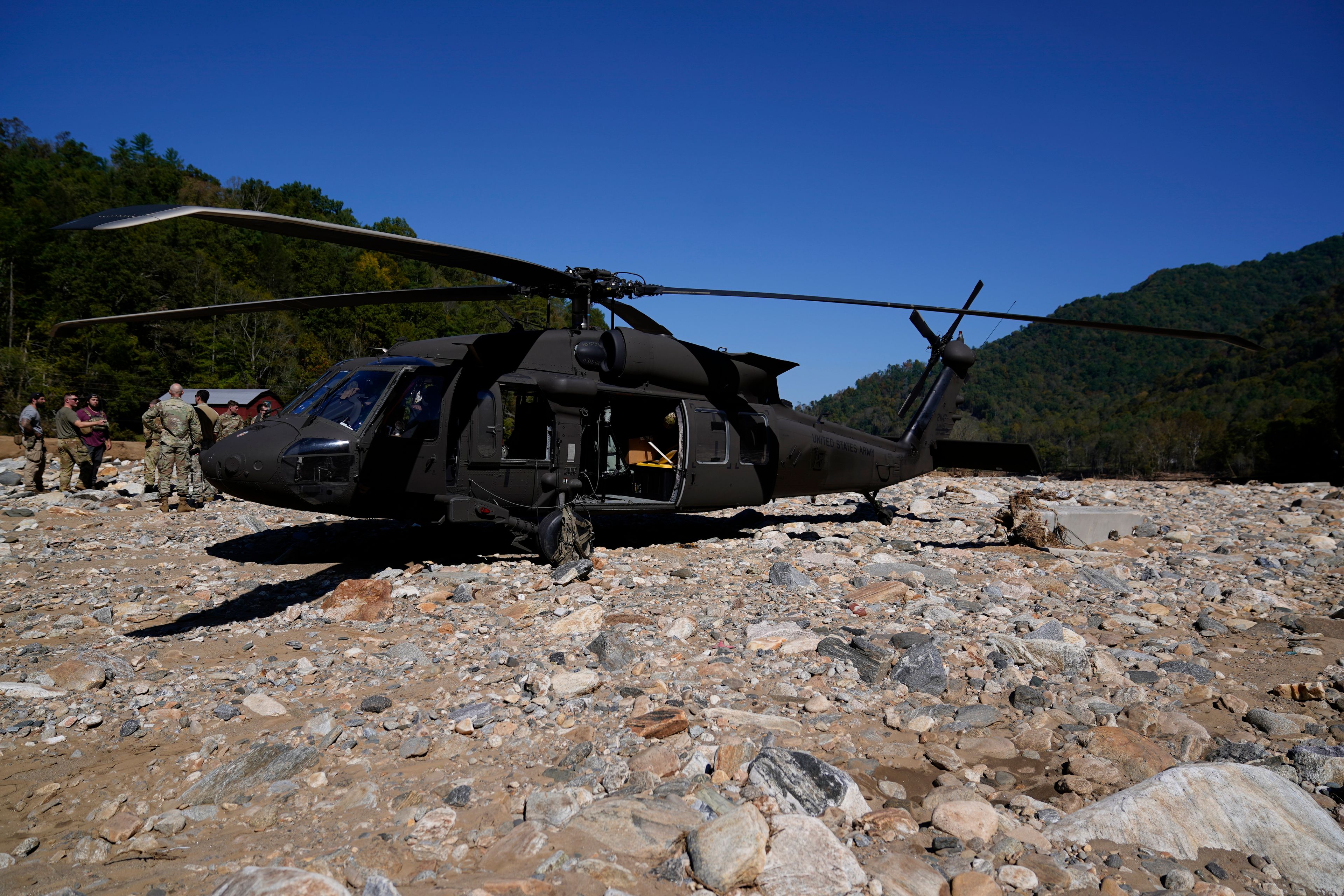 National Guard members stand outside of a Black Hawk helicopter during a supply delivery assignment on Tuesday, Oct. 8, 2024, in Burnsville, N.C. (AP Photo/Erik Verduzco)