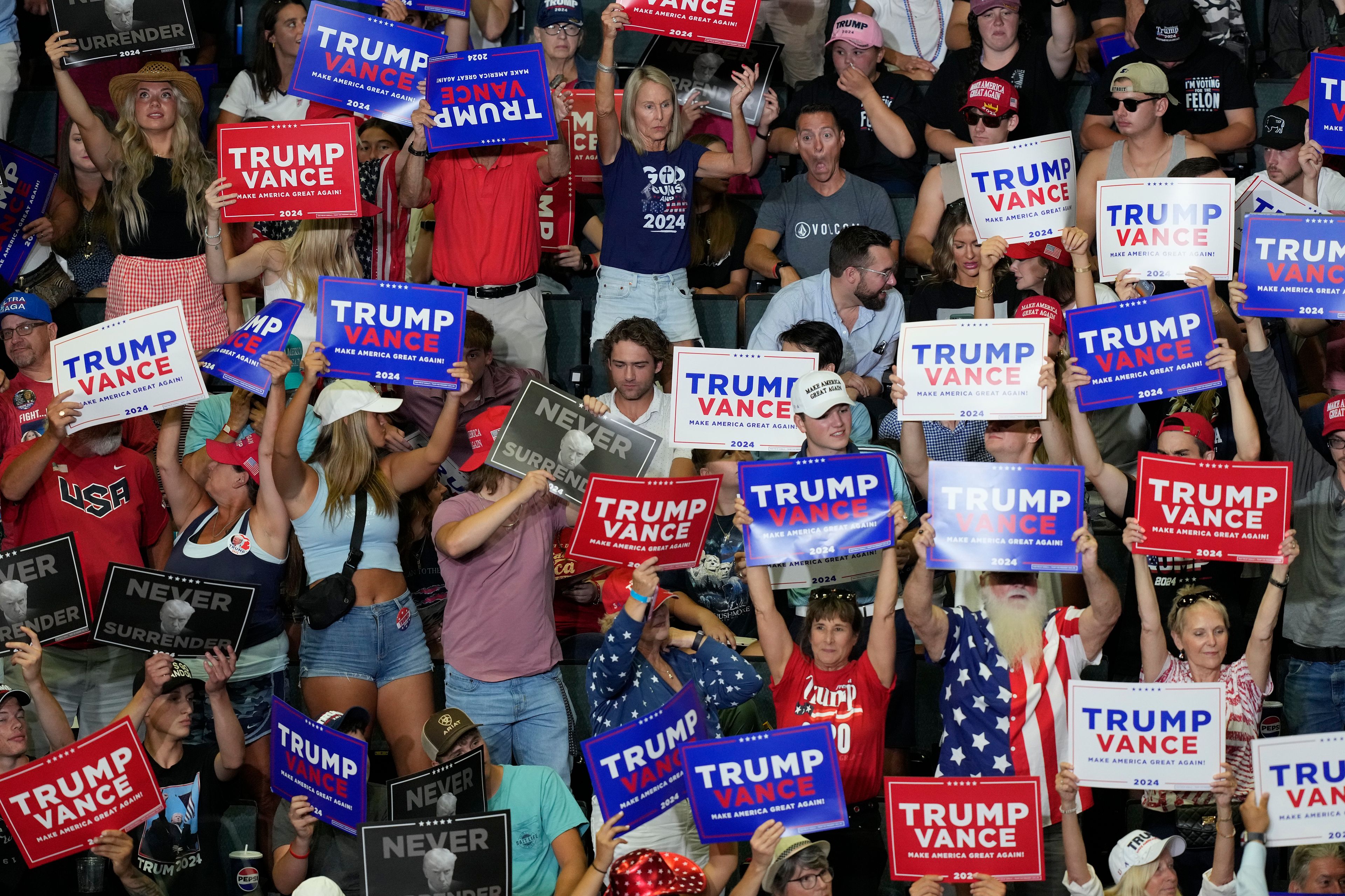 Supporters of Republican presidential candidate former President Donald Trump and Republican vice presidential candidate Sen. JD Vance, R-Ohio, hold signs in the audience at a campaign event, Saturday, July 20, 2024, at Van Andel Arena in Grand Rapids, Mich. (AP Photo/Carlos Osorio)