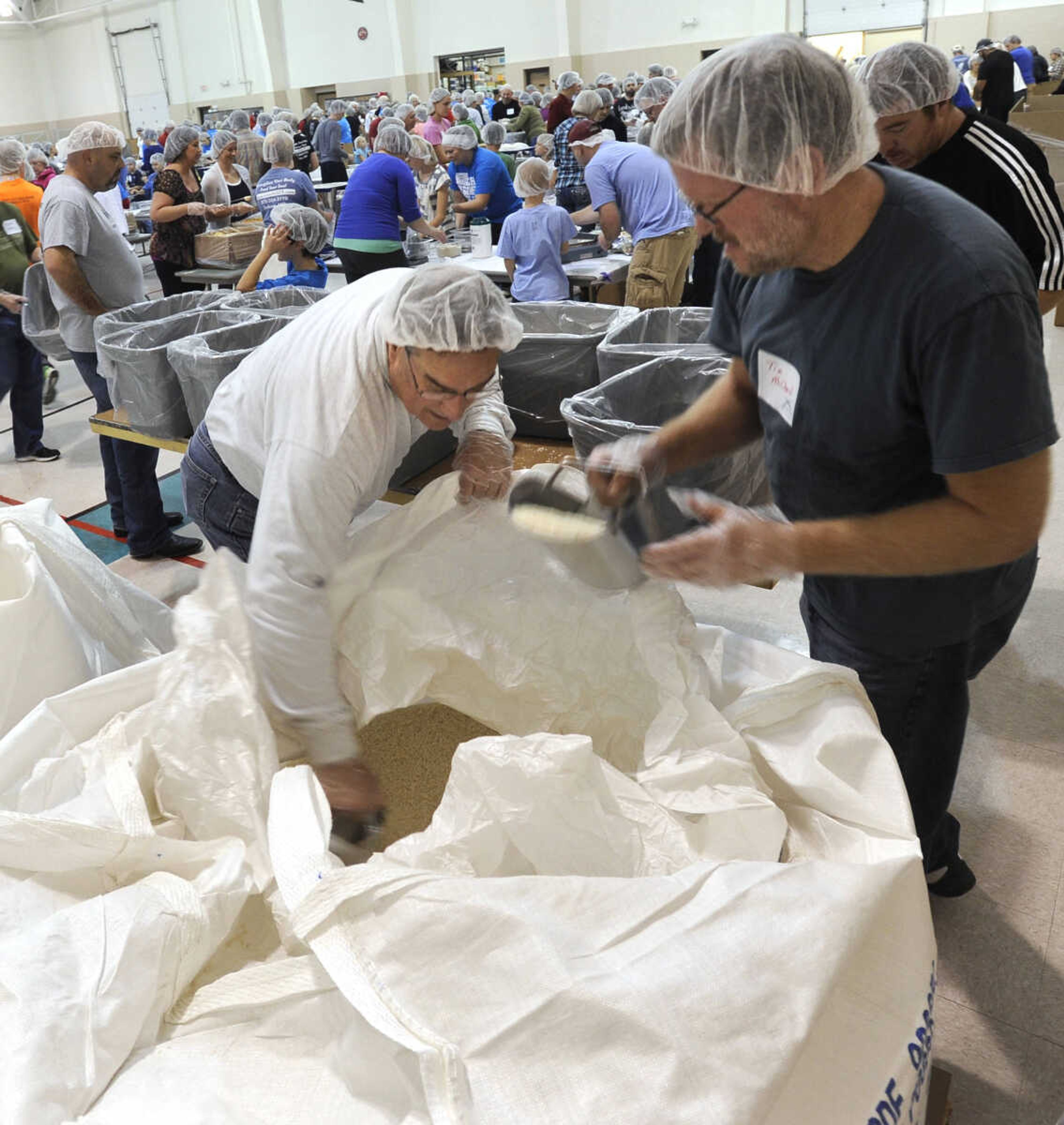 John Caldwell, left, and Tim McClard scoop rice to fill the bins for the packing lines.